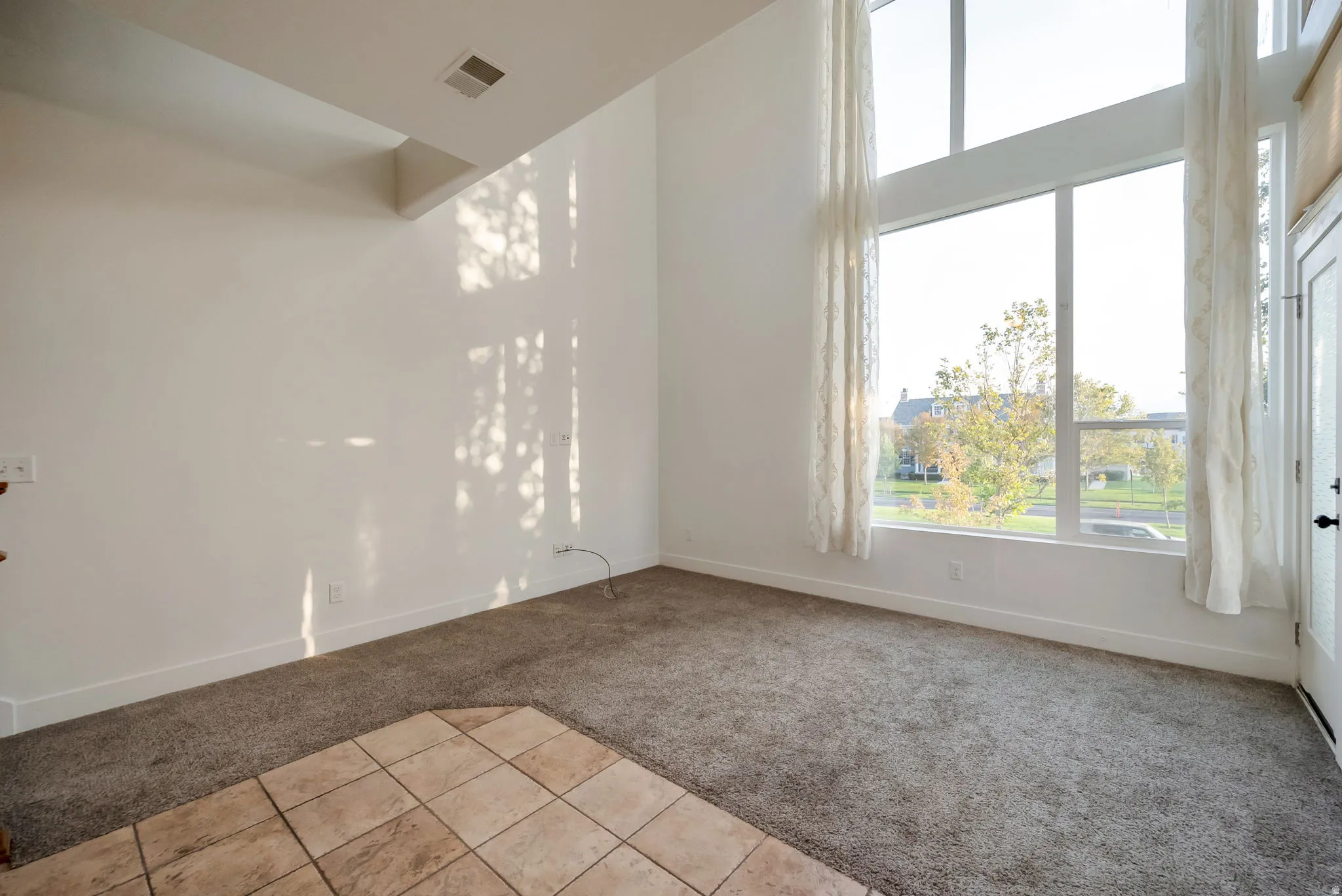 Spare room featuring light carpet and light tile patterned flooring