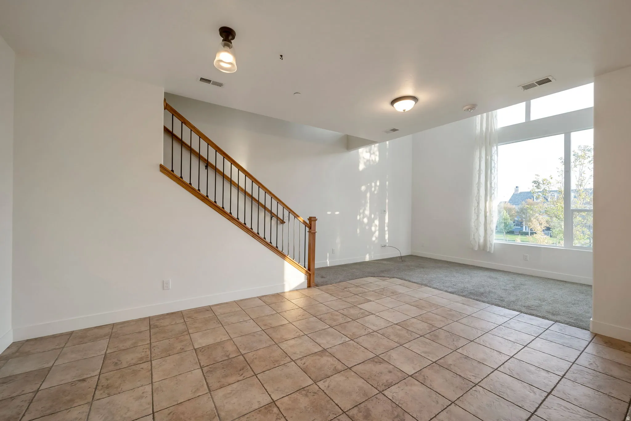Unfurnished living room with stairway and tile patterned flooring