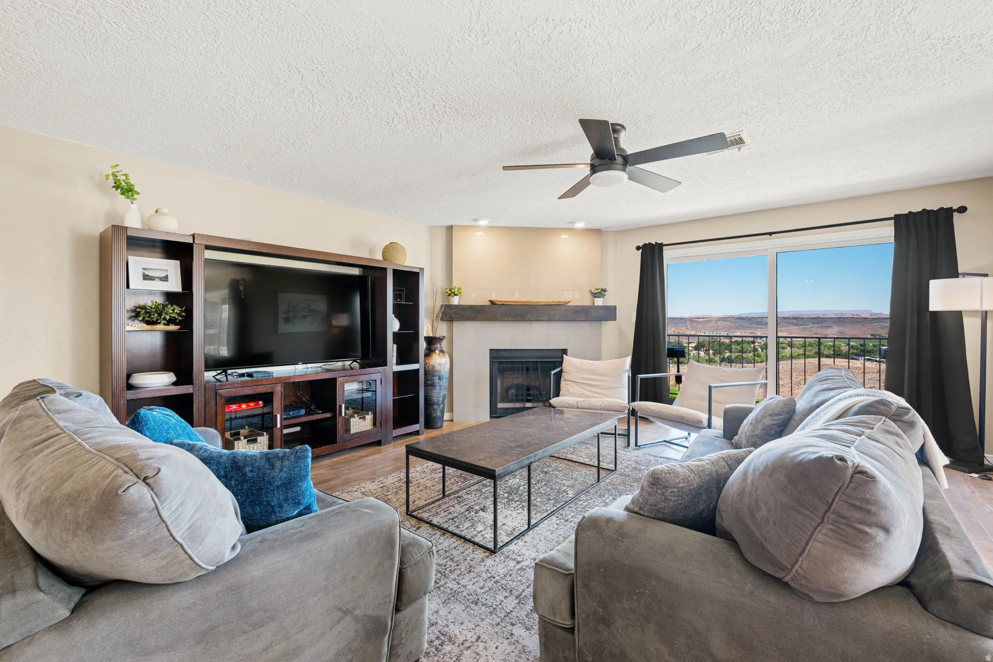 Living area with wood finished floors, a fireplace, a textured ceiling, and a ceiling fan