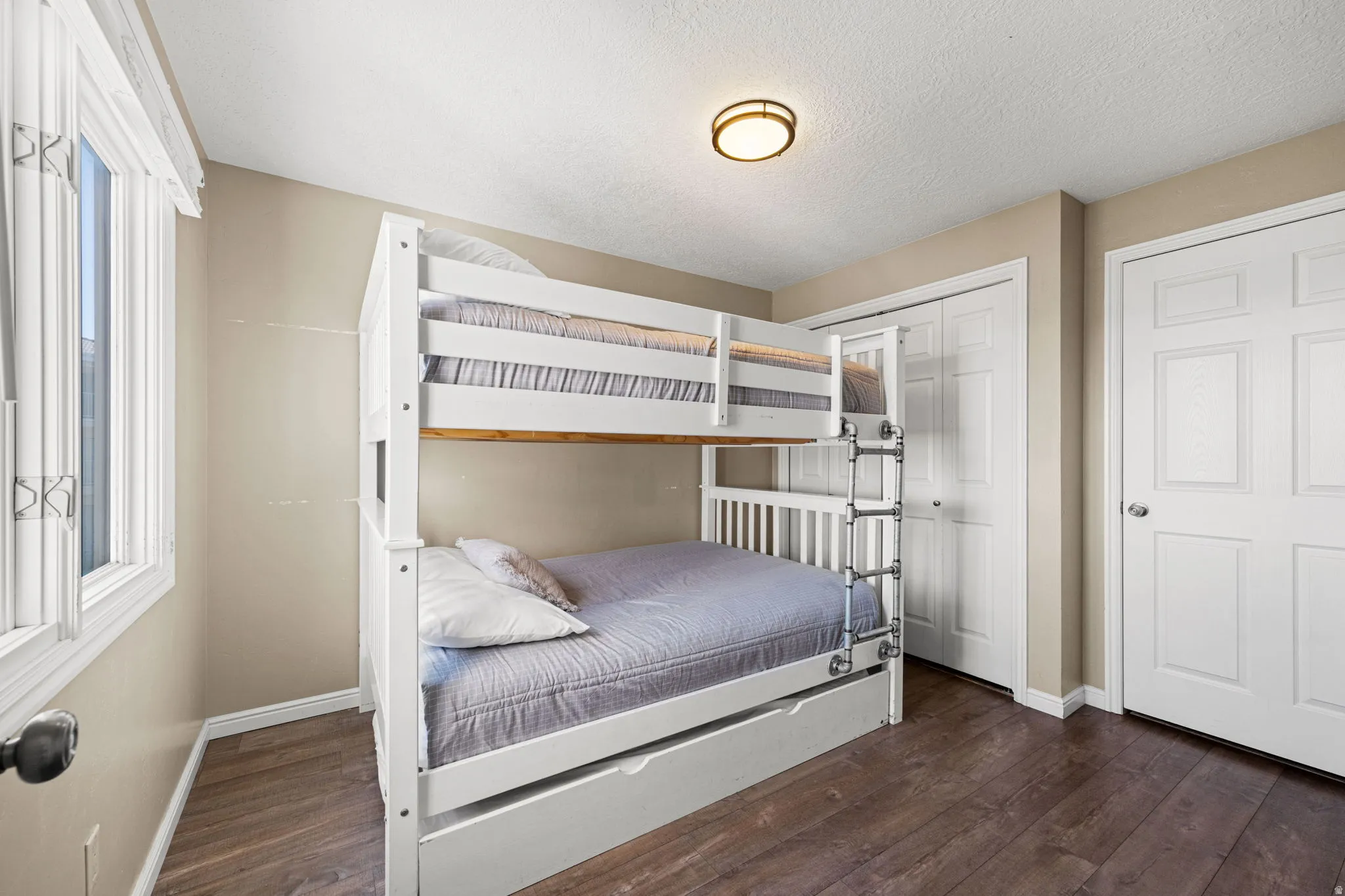 Bedroom with dark wood finished floors, a closet, and a textured ceiling