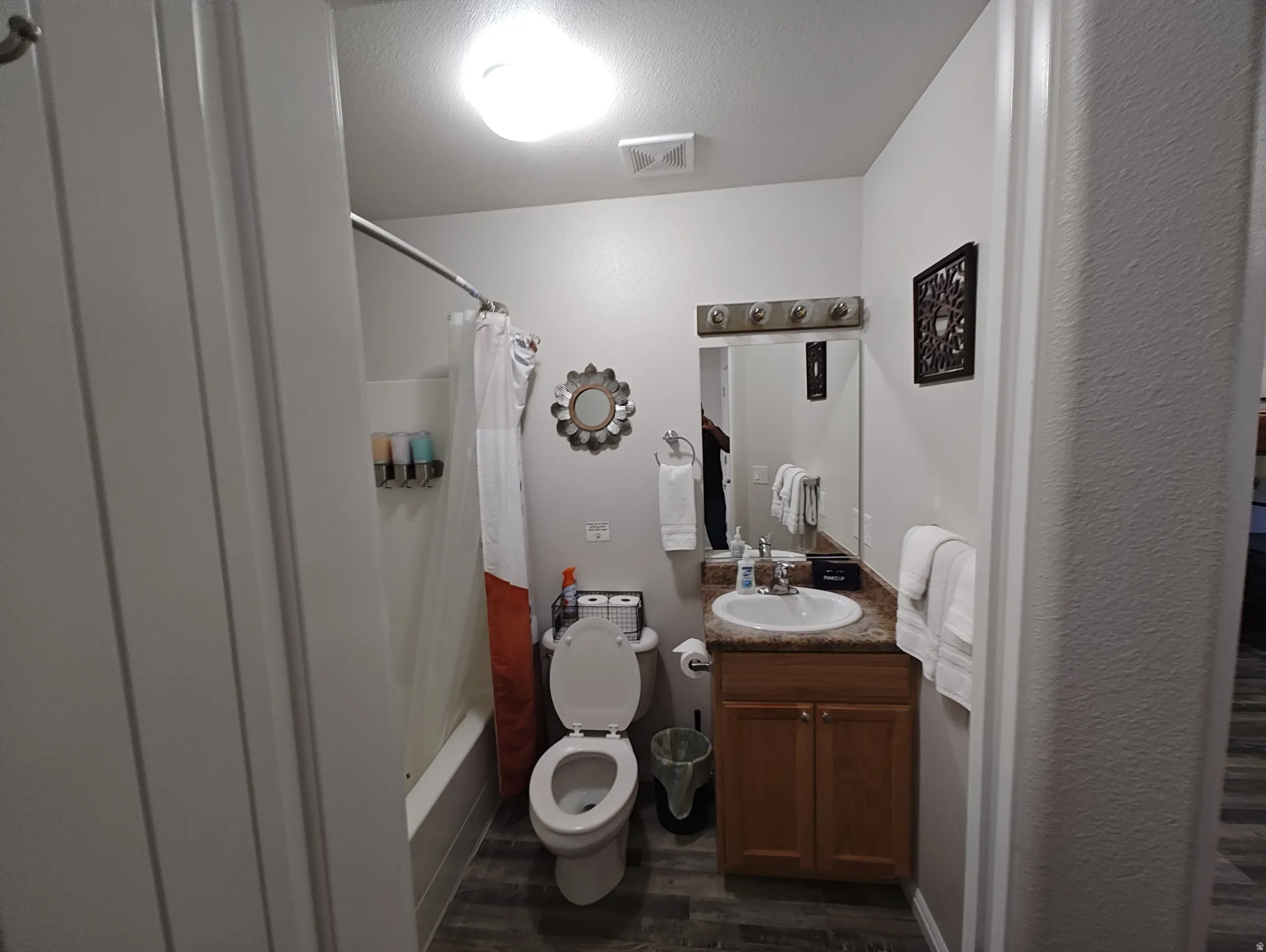 Bathroom featuring shower / bath combo, vanity, dark wood-style flooring, and a textured ceiling