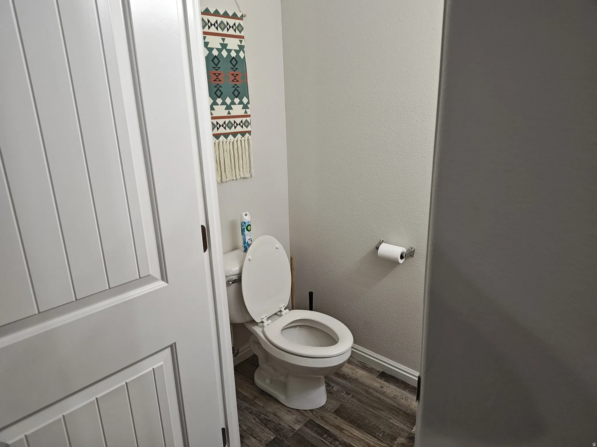 Bathroom featuring dark wood-style flooring and a textured wall