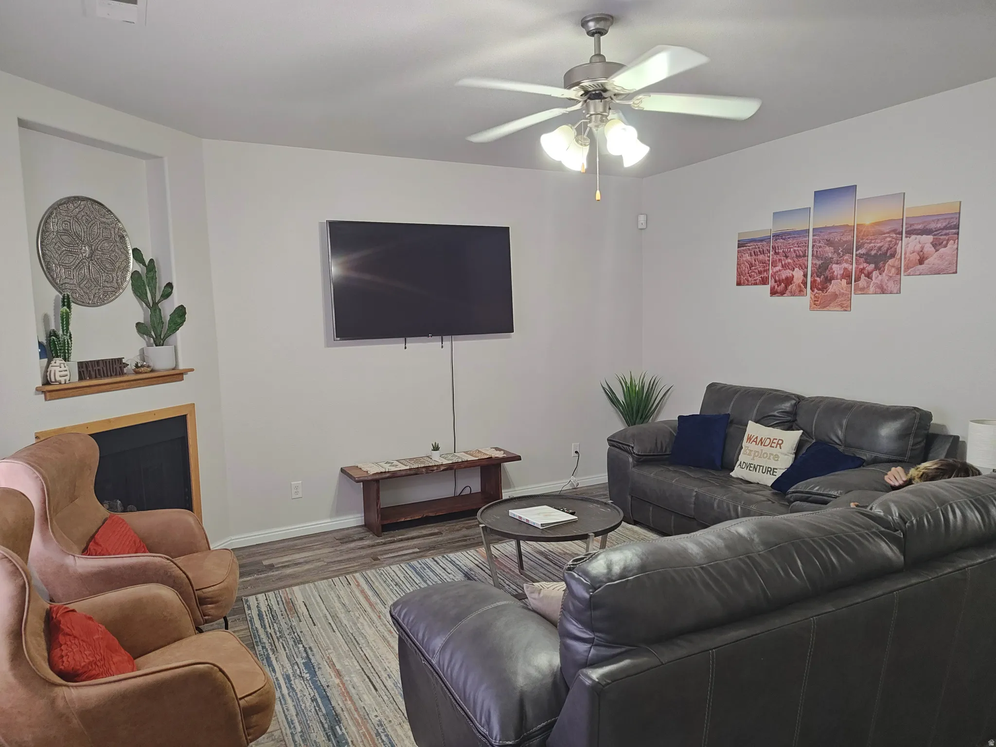 Living room featuring wood finished floors, ceiling fan, and a fireplace