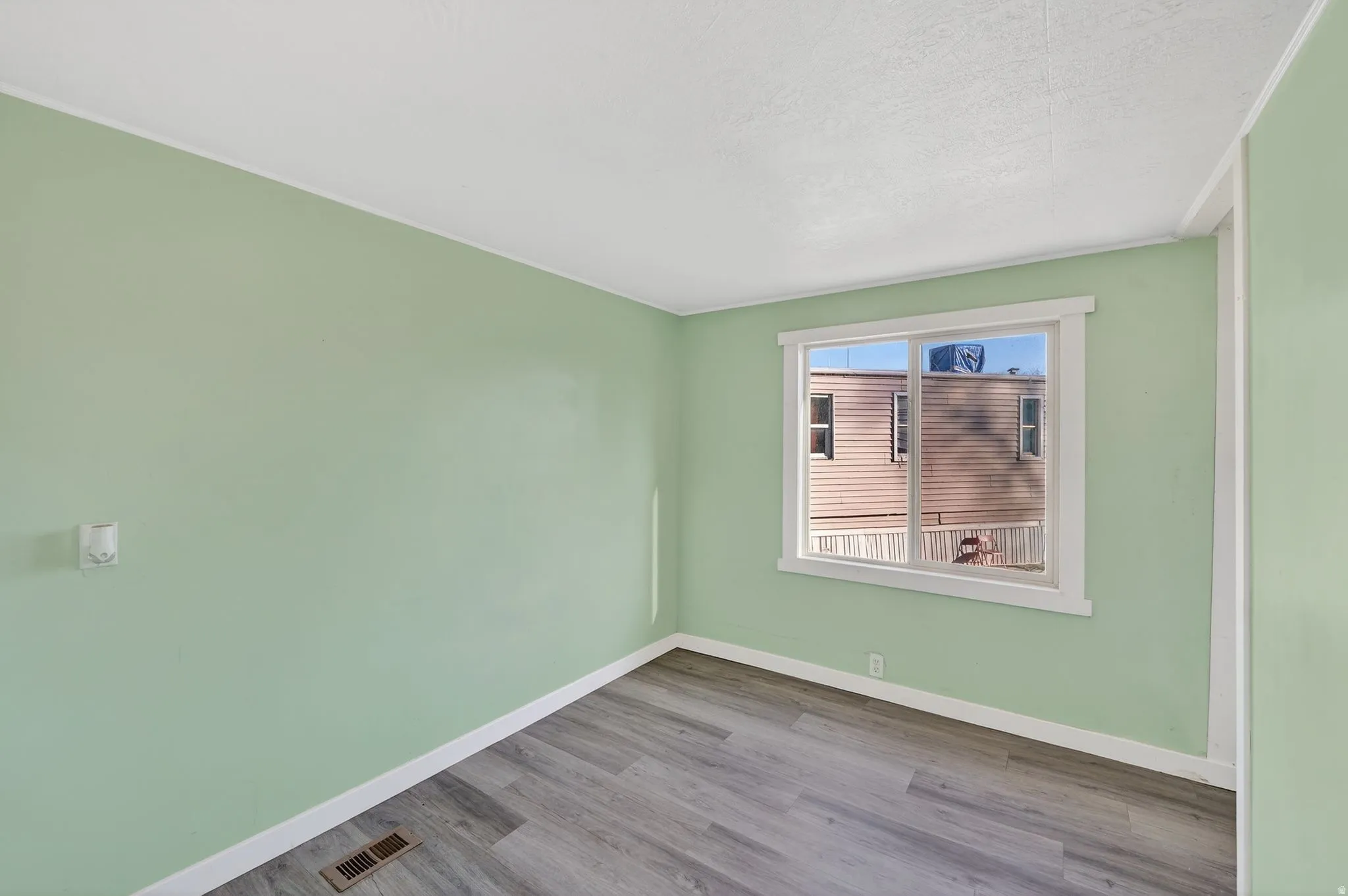 Empty room with wood finished floors and a textured ceiling