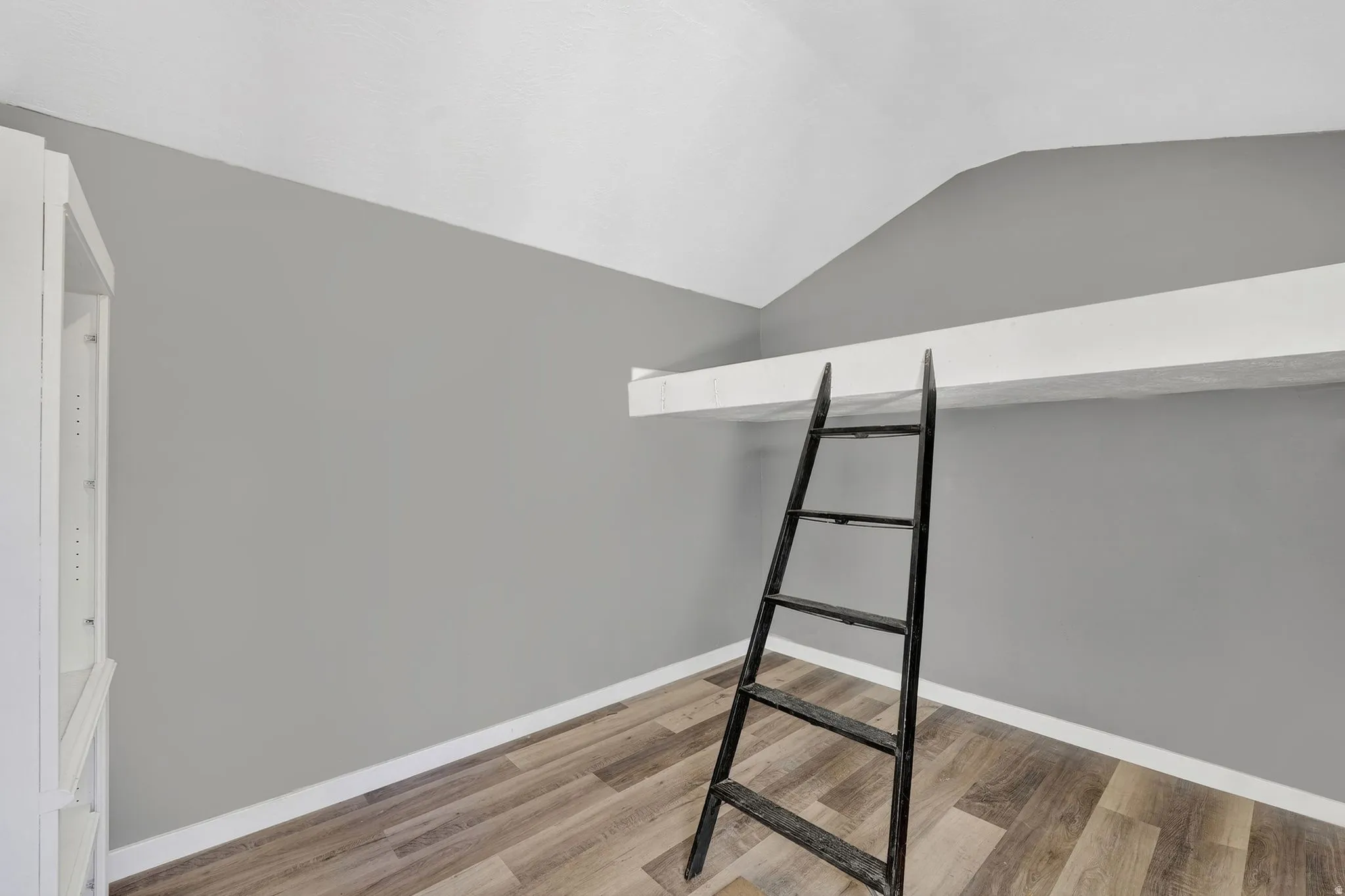 Unfurnished bedroom with lofted ceiling and light wood-style floors