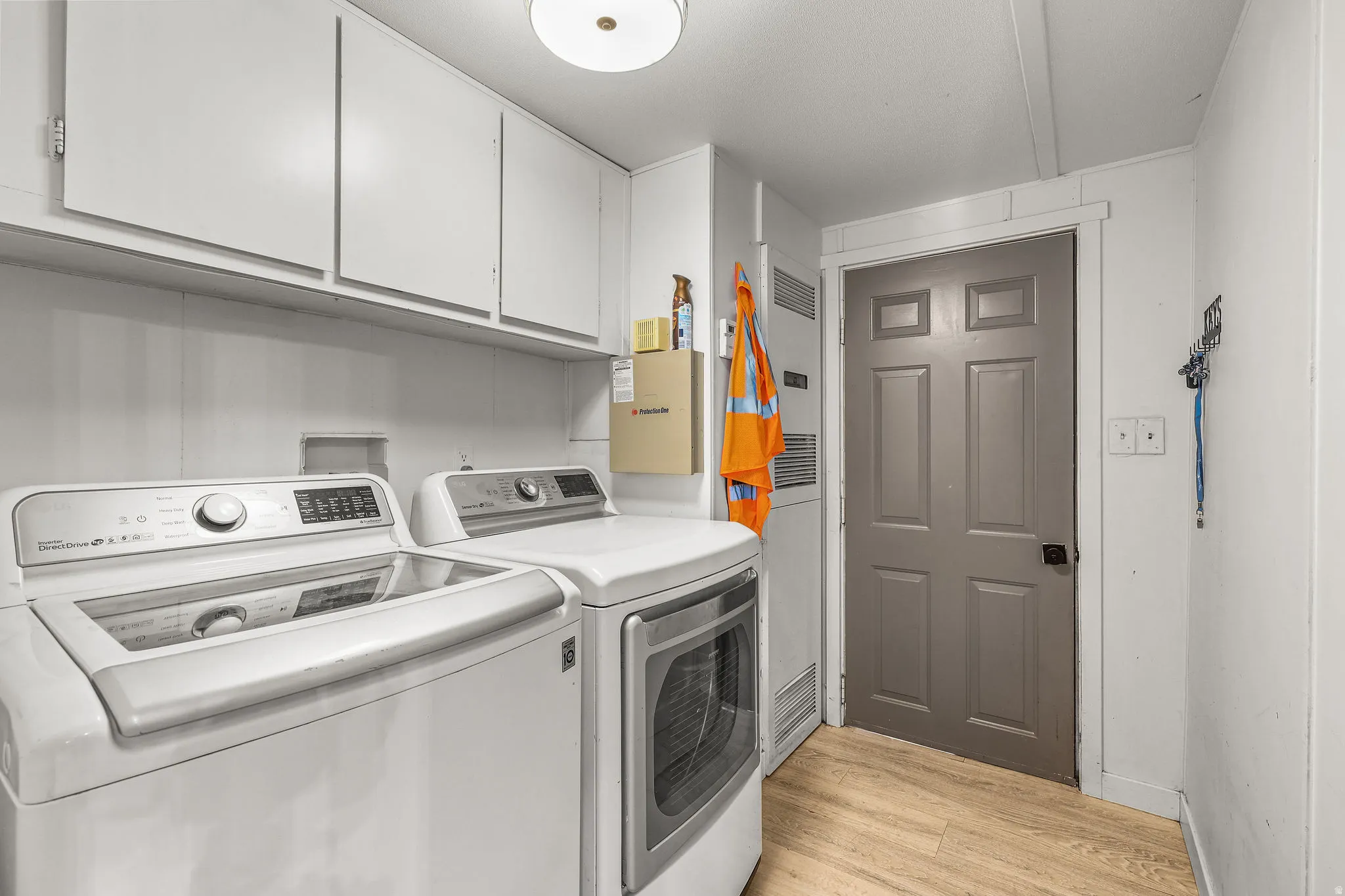 Laundry room with washing machine and dryer, light wood-style floors, and cabinet space