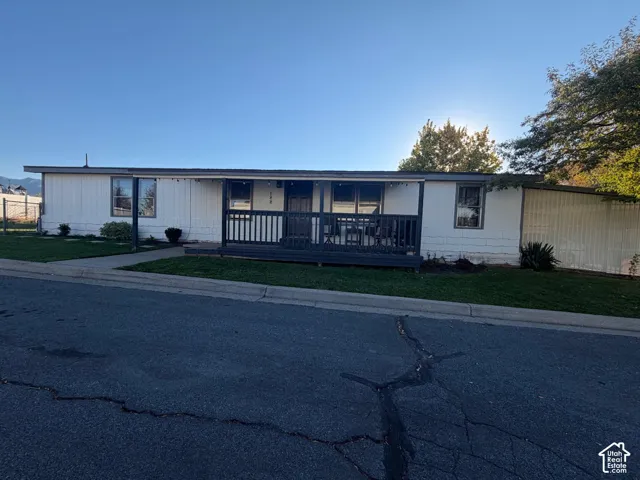 Charming manufactured home featuring a welcoming front entrance with a covered porch, metal siding exterior, and large windows allowing natural light throughout