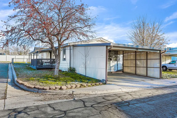 View of home's exterior with driveway, an attached carport, and a wooden deck