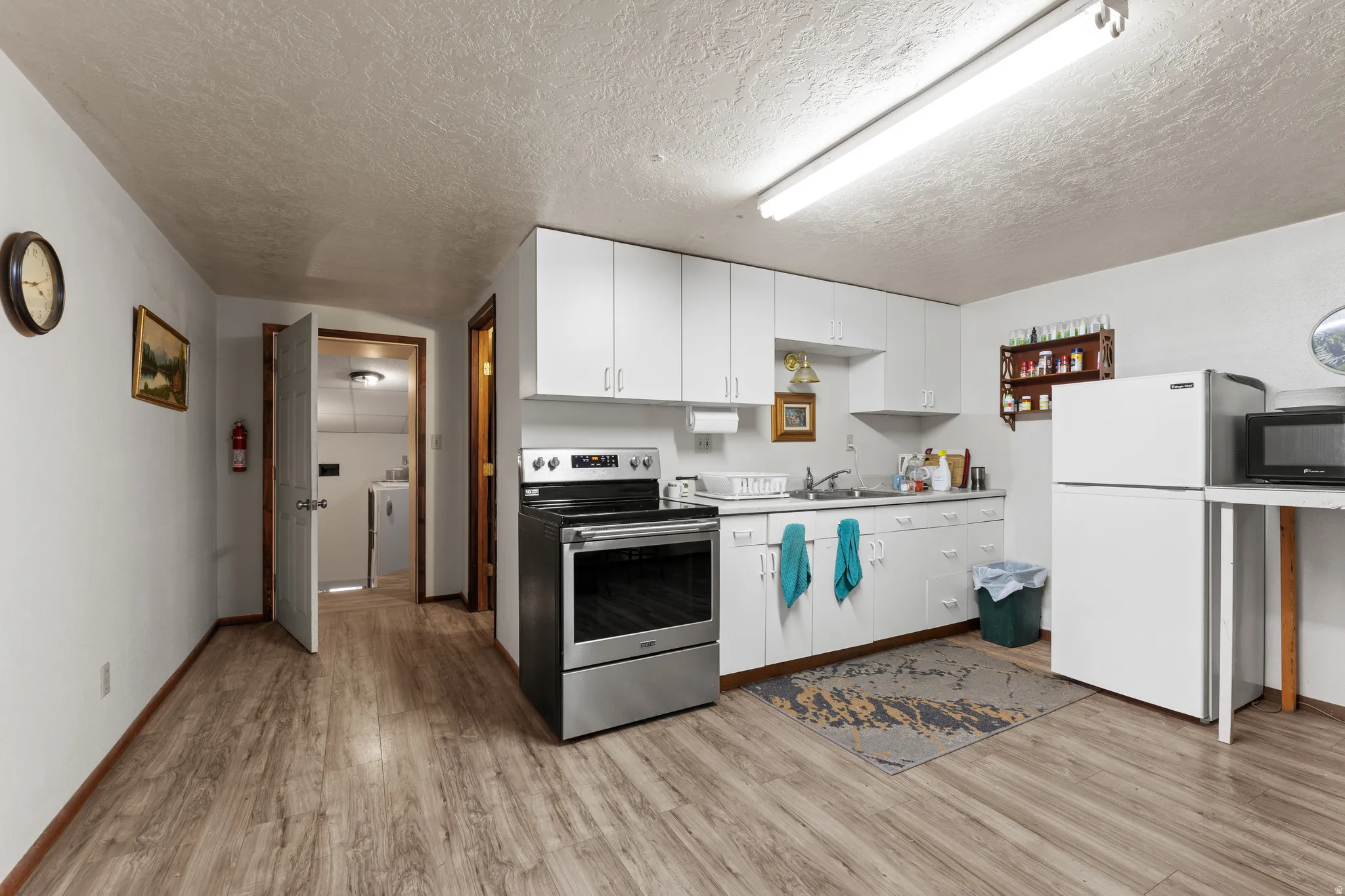 Kitchen with white cabinets, electric range, freestanding refrigerator, black microwave, and light countertops