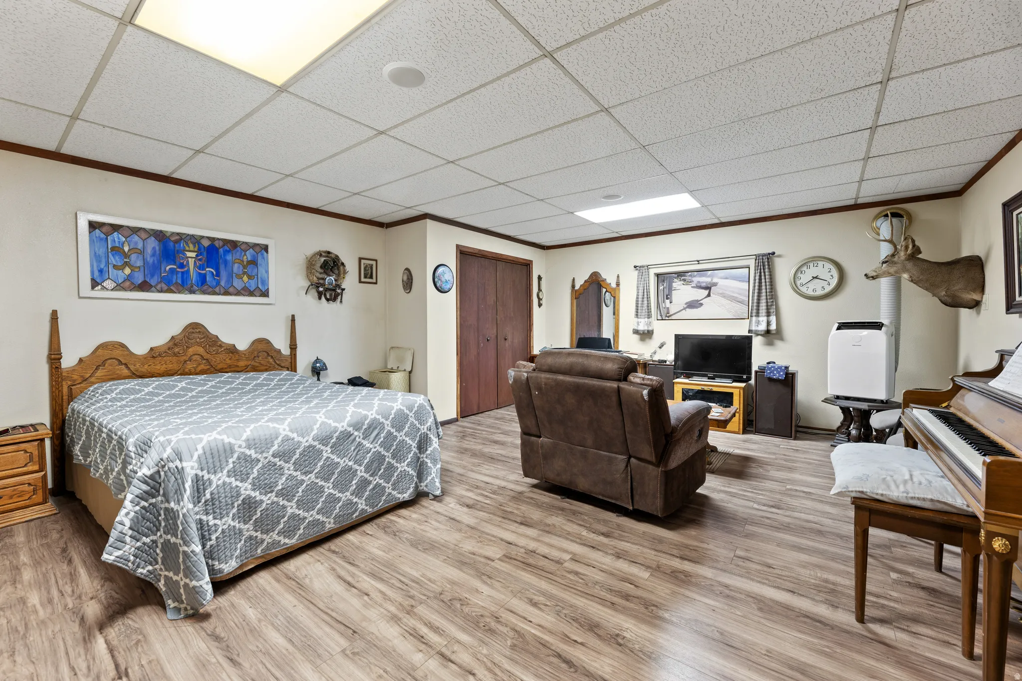 Bedroom with crown molding, wood finished floors, a drop ceiling, and a closet
