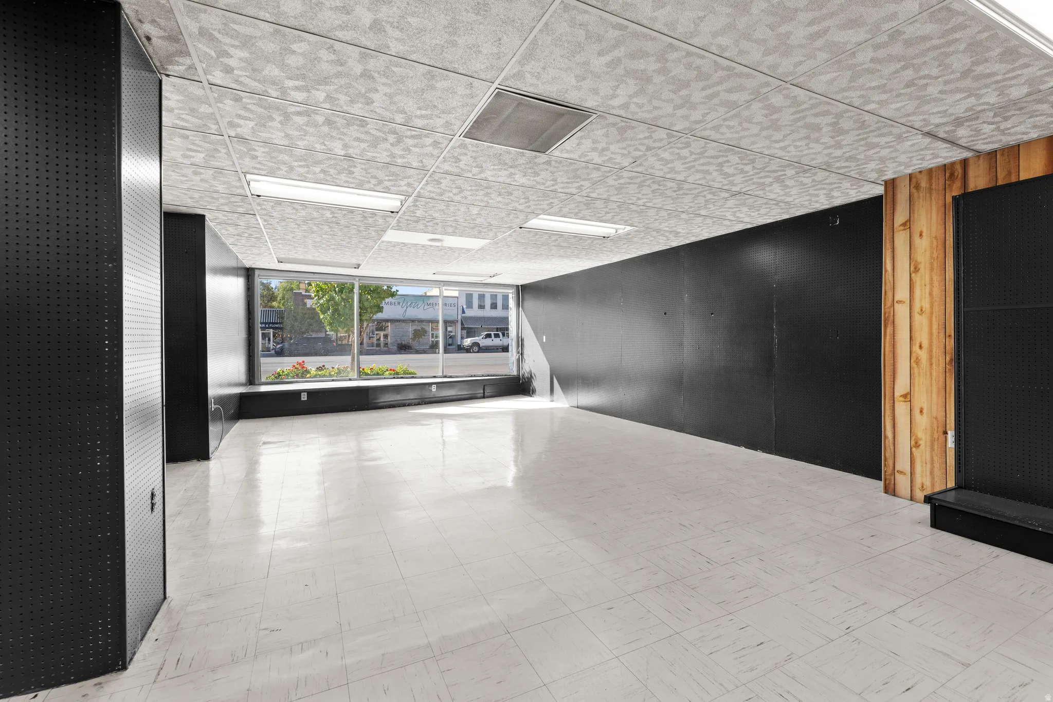 Hallway with light flooring and a paneled ceiling