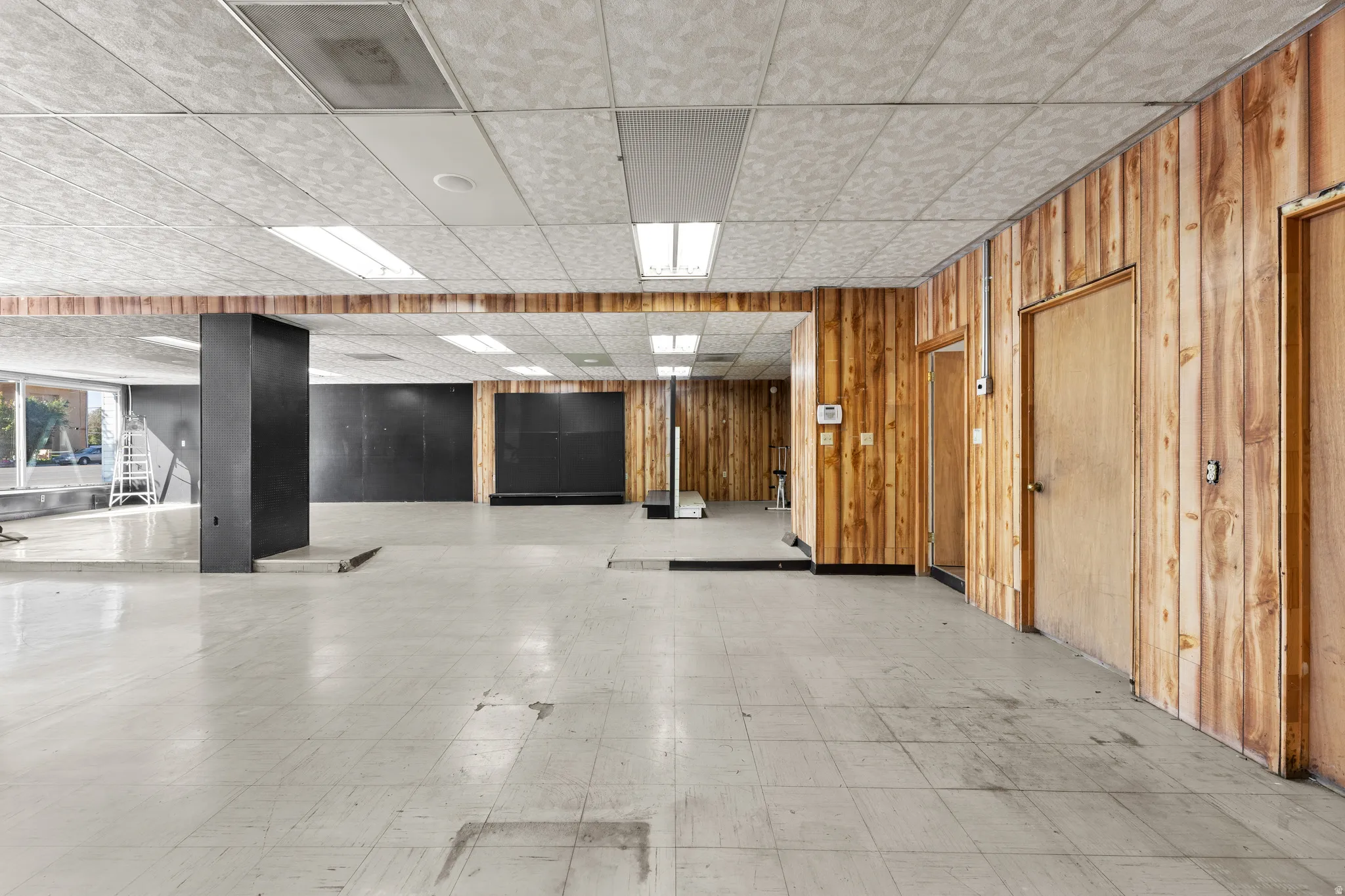 Misc room with a drop ceiling, tile patterned floors, and wooden walls