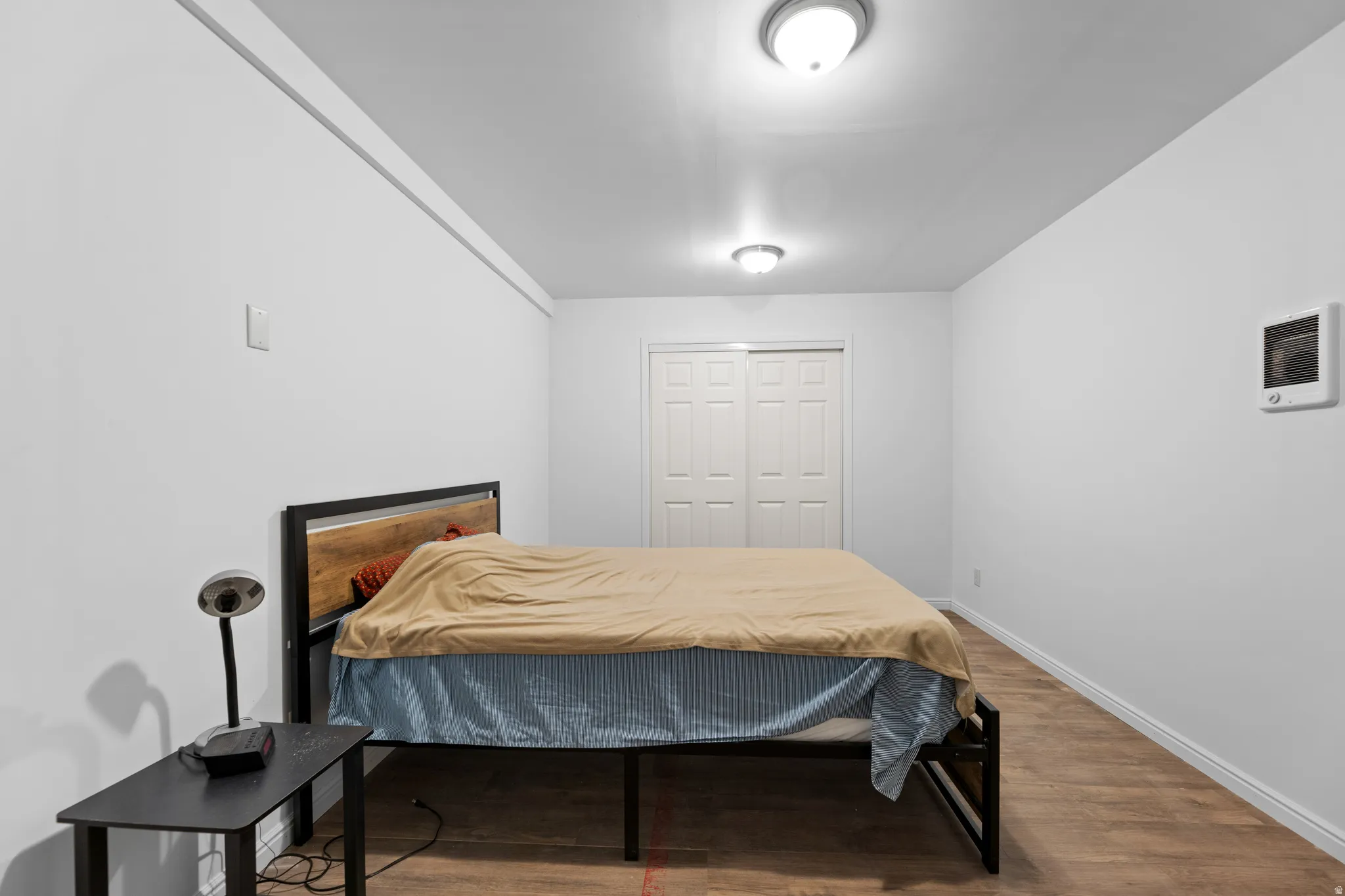 Bedroom with wood finished floors and a closet