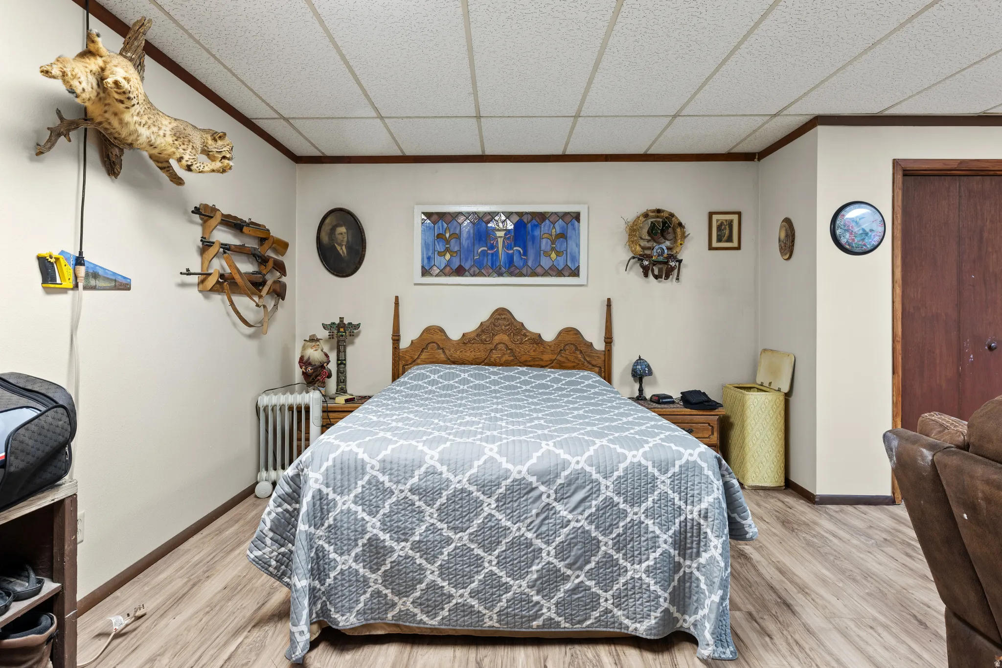Bedroom with a drop ceiling, light wood-style floors, and radiator heating unit