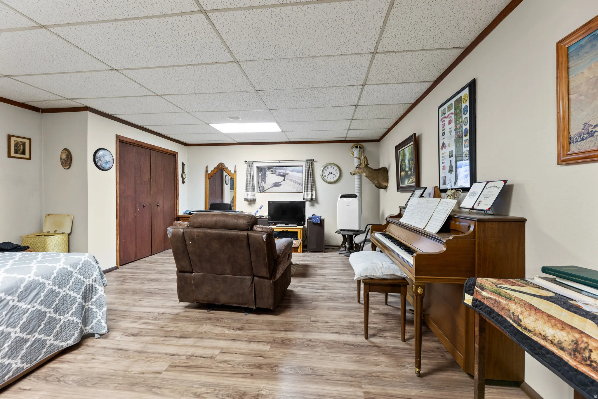 Living room featuring light wood-style floors, a paneled ceiling, and crown molding