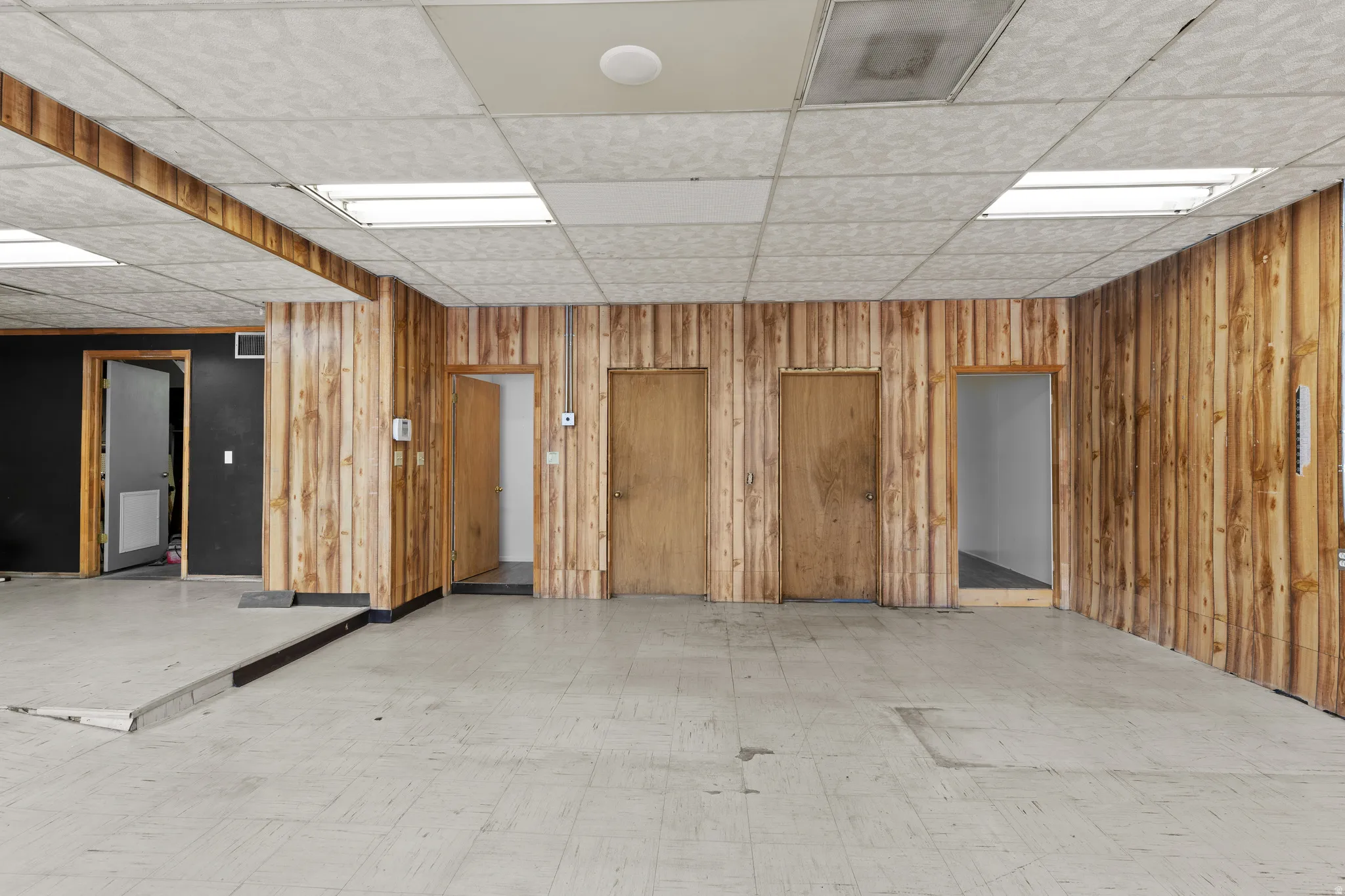 Basement with light floors, wooden walls, and a drop ceiling