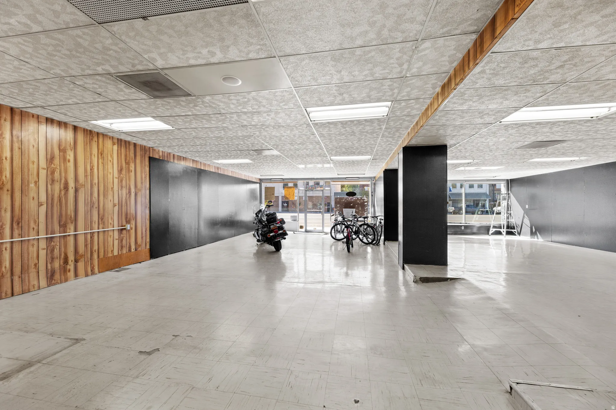 Miscellaneous room with wooden walls, floor to ceiling windows, and a drop ceiling