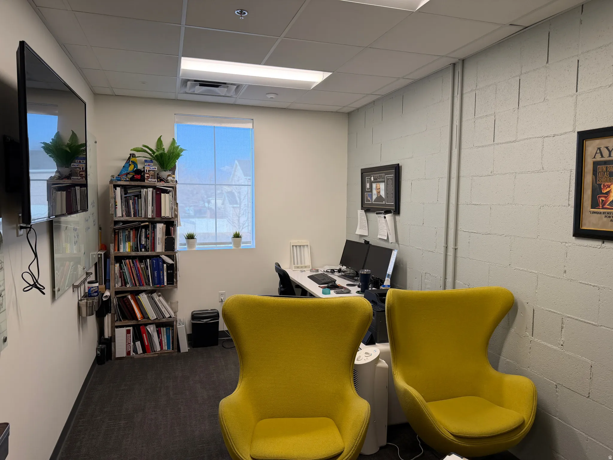 Office featuring concrete block wall, dark carpet, and a drop ceiling