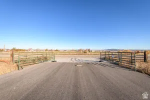 View of asphalt road featuring an enclosed riding area and a rural view
