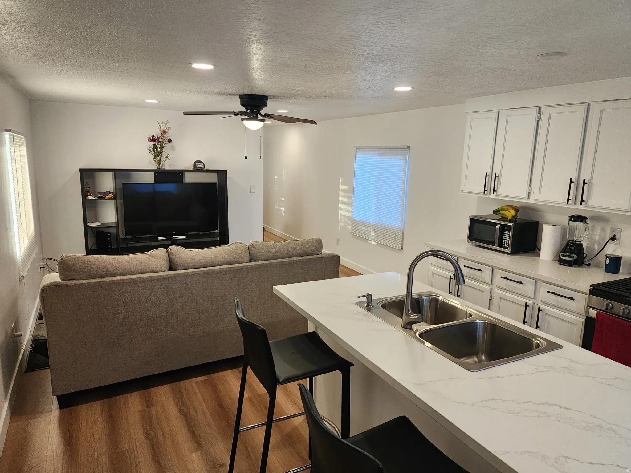 Kitchen featuring white cabinetry, recessed lighting, a kitchen bar, dark wood finished floors, and appliances with stainless steel finishes