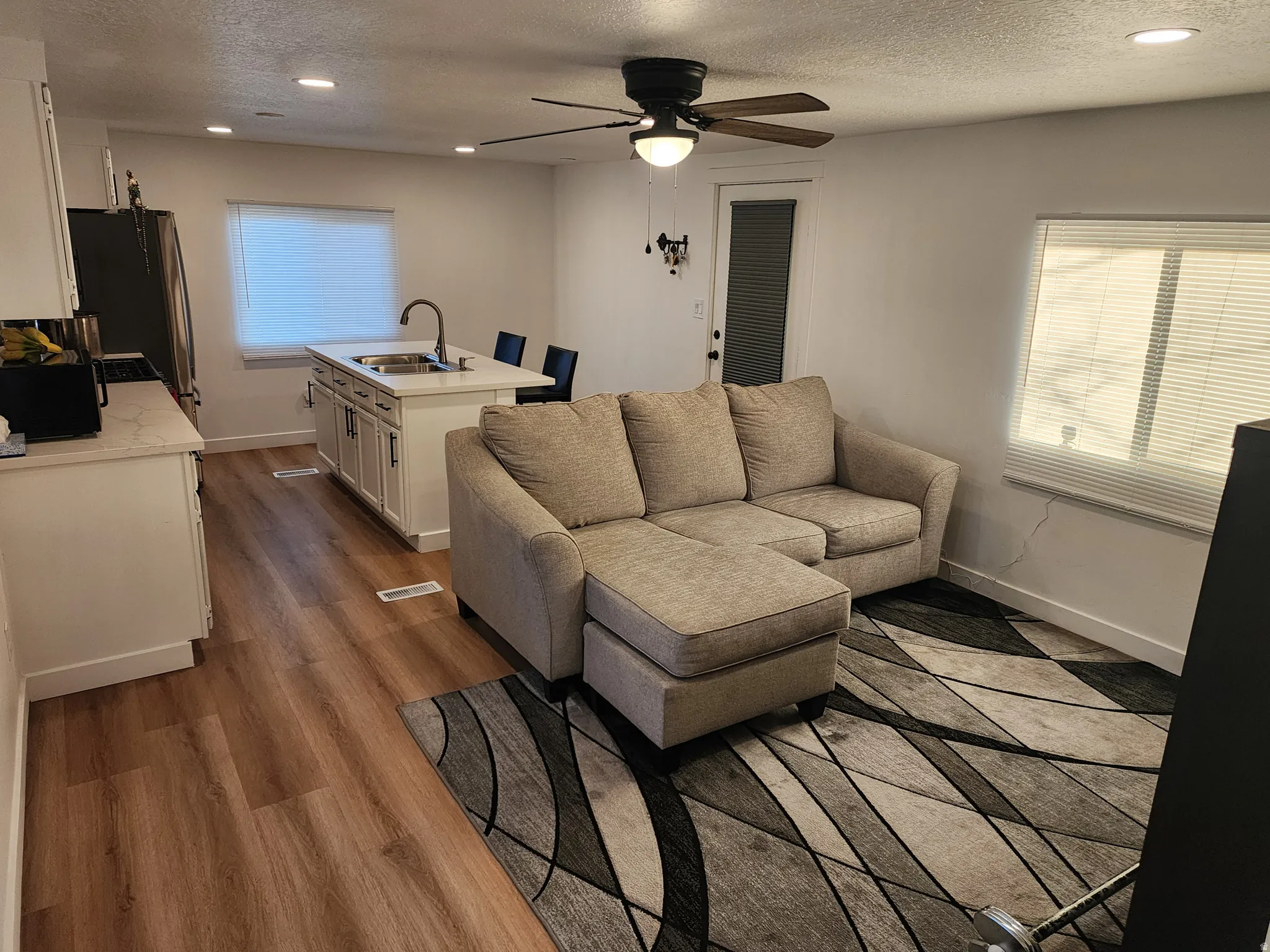 Living area featuring a textured ceiling, dark wood-type flooring, ceiling fan, recessed lighting, and plenty of natural light