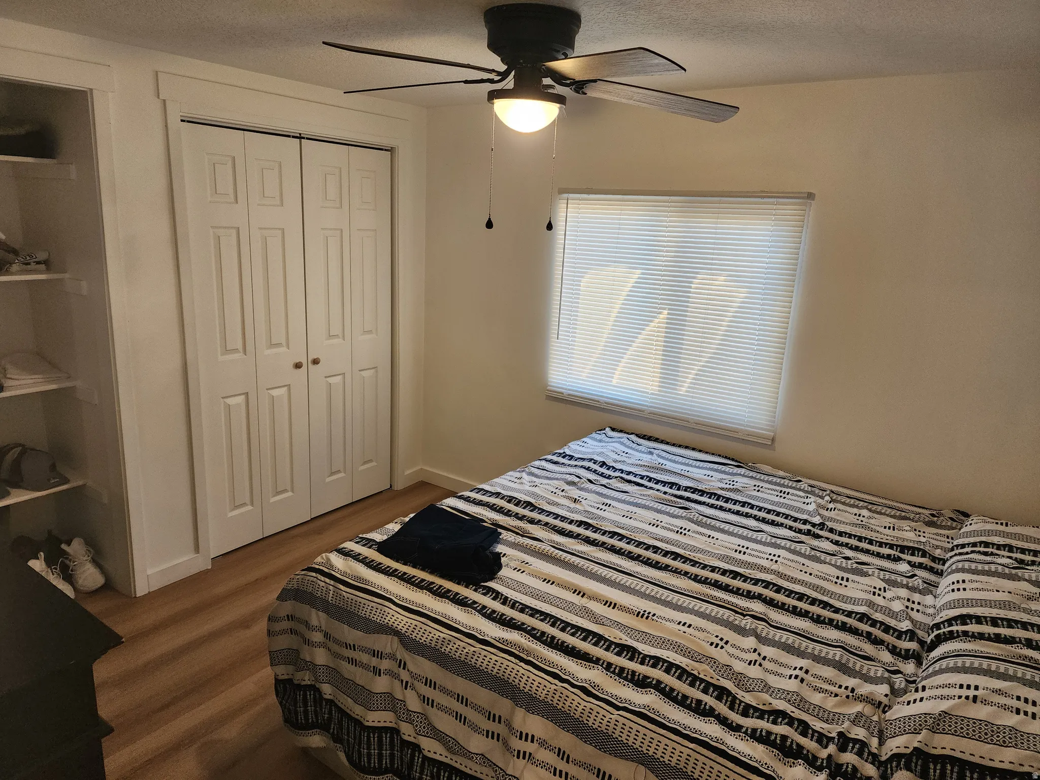 Bedroom featuring dark wood-type flooring, a closet, a ceiling fan, and a textured ceiling