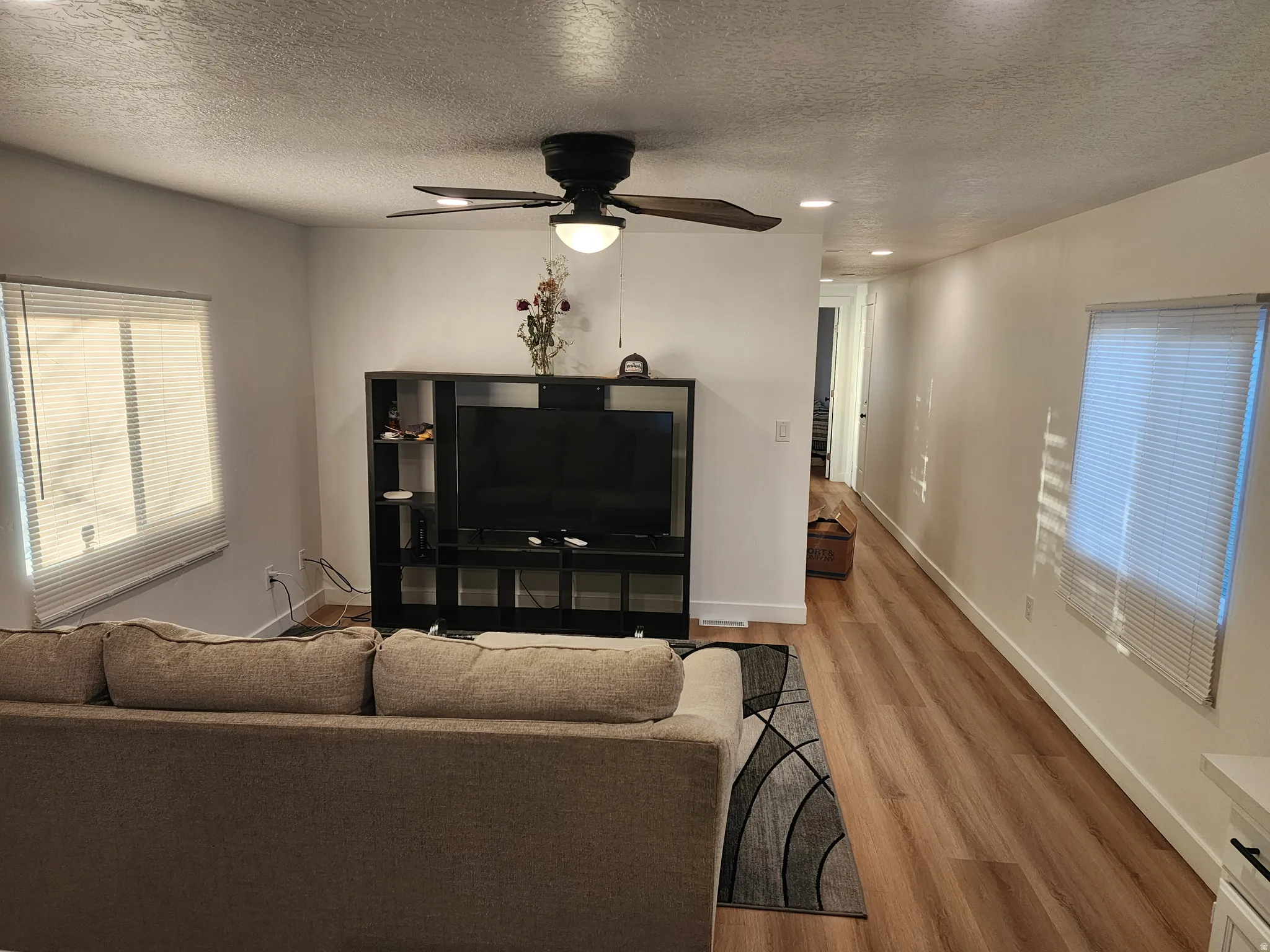 Living room featuring wood finished floors, a textured ceiling, a ceiling fan, and recessed lighting