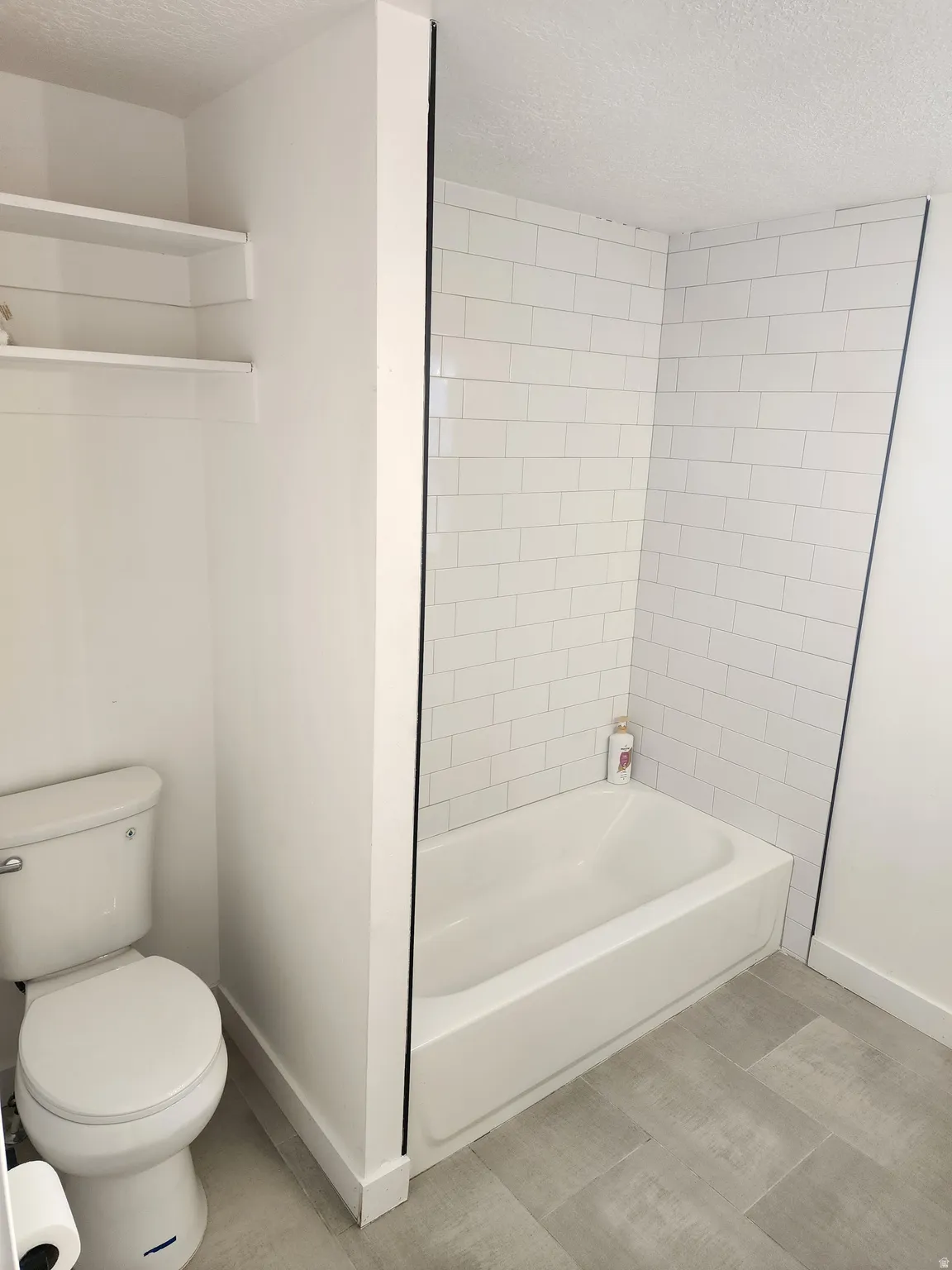 Bathroom with a textured ceiling and tub / shower combination