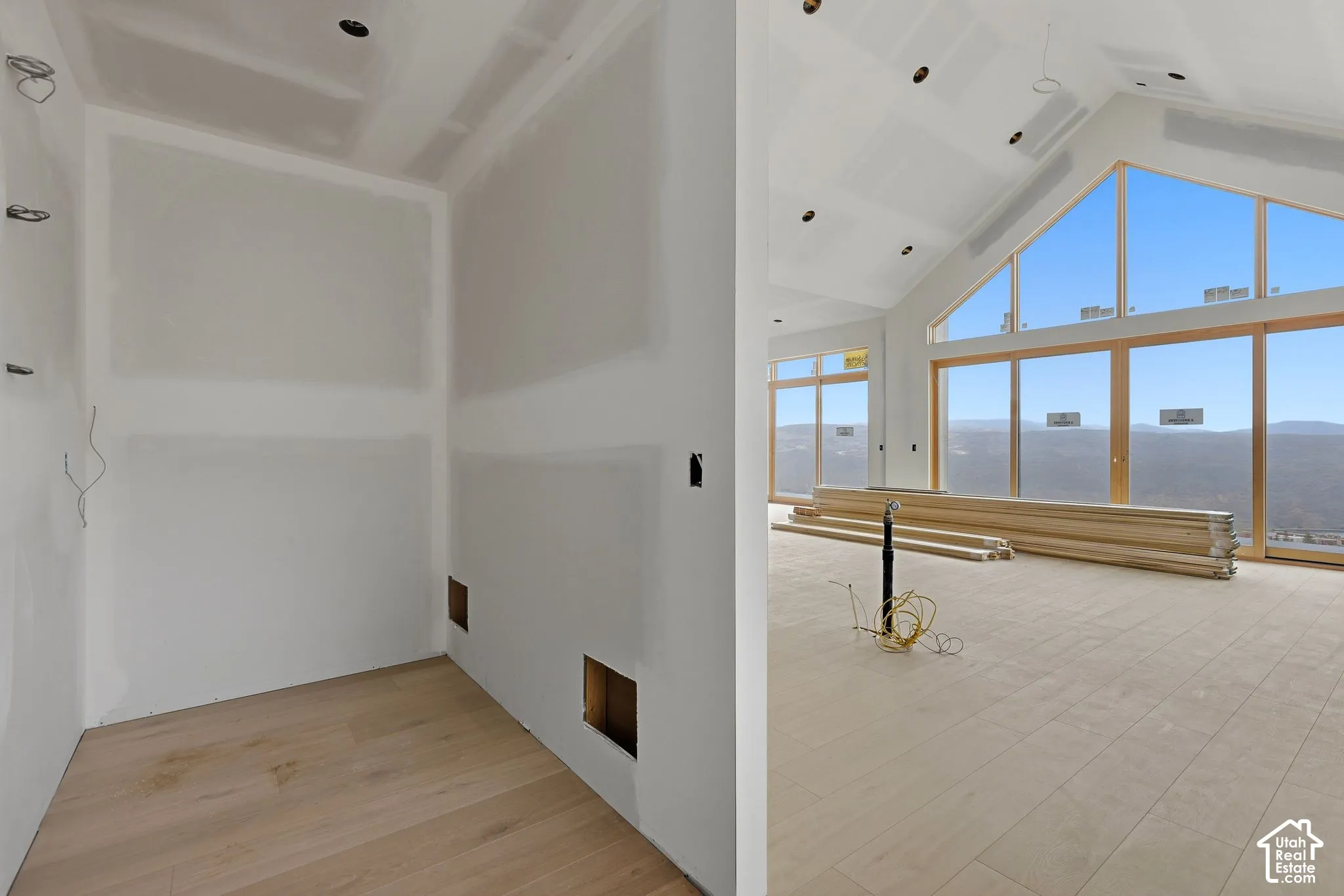 Vaulted ceilings, extensive floor-to-ceiling windows, mountain scenery, and light-tone wood-finish flooring