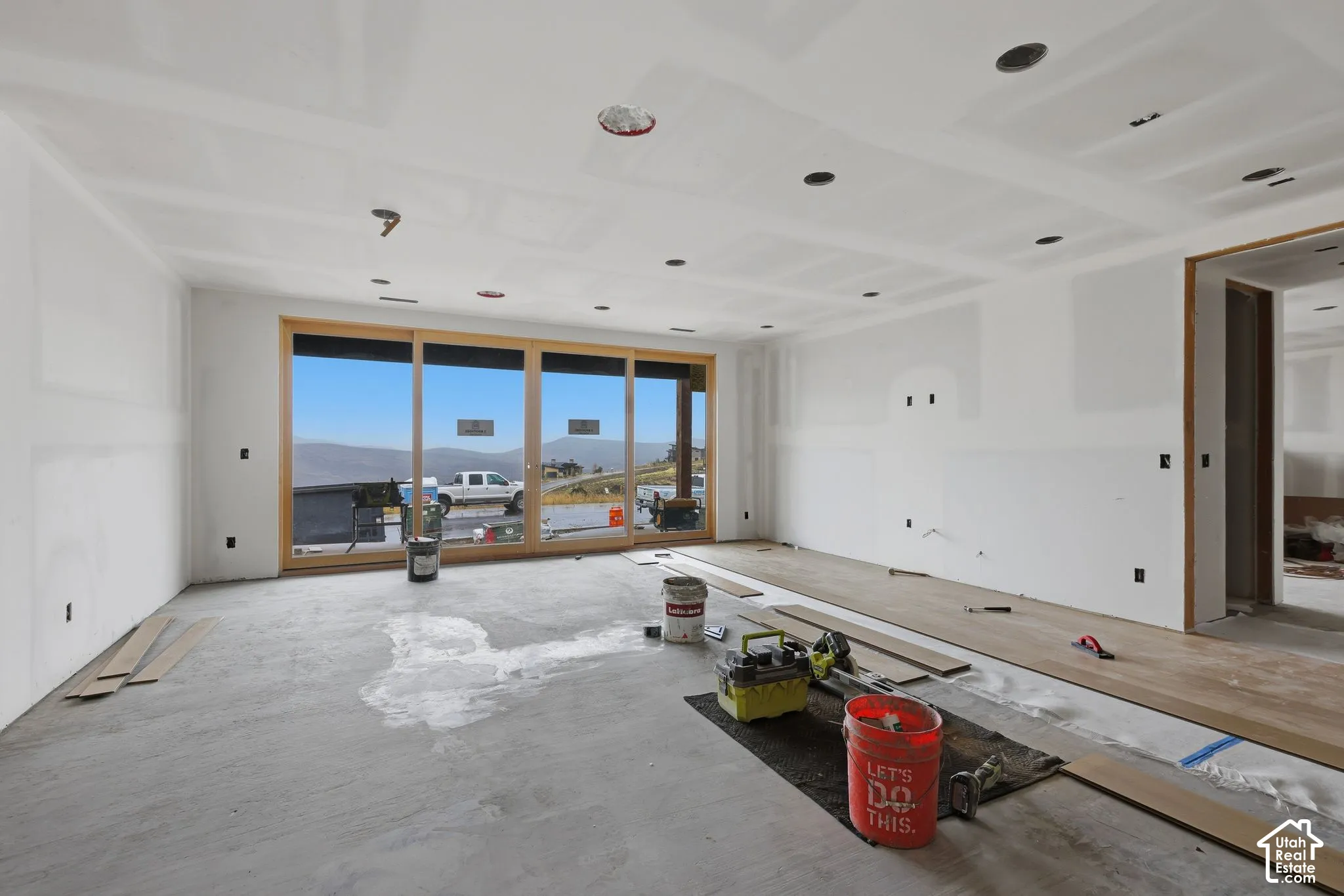 Expansive interior space featuring a multi-panel sliding glass door system, recessed ceiling lighting, and wood-finish flooring