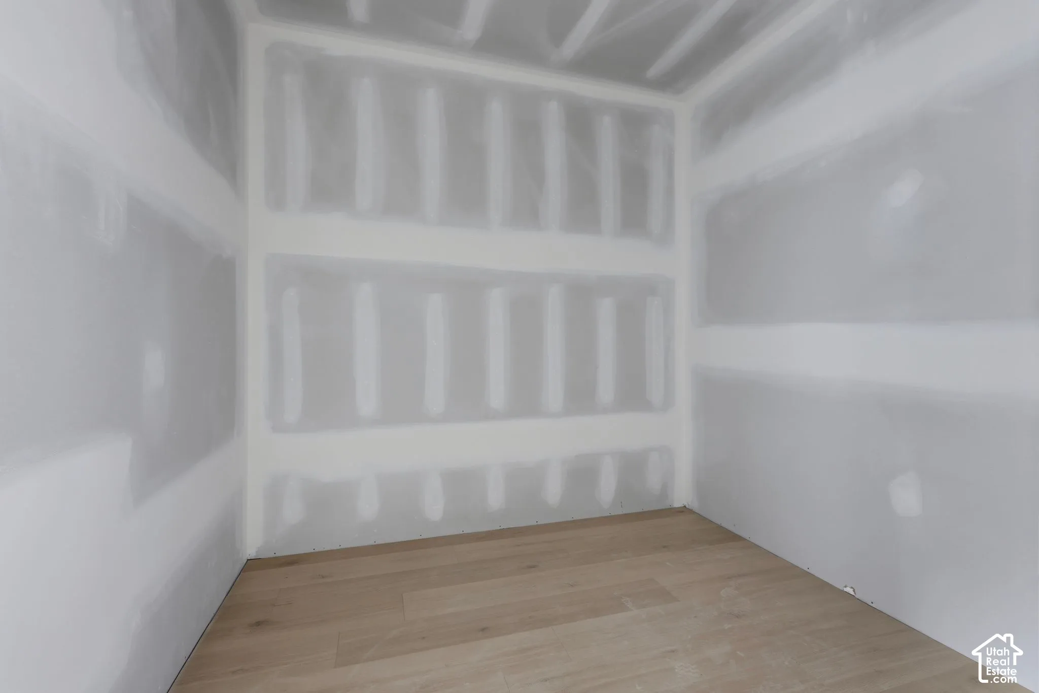 Unfinished interior space featuring drywall with taped seams and light-toned wood-finish flooring