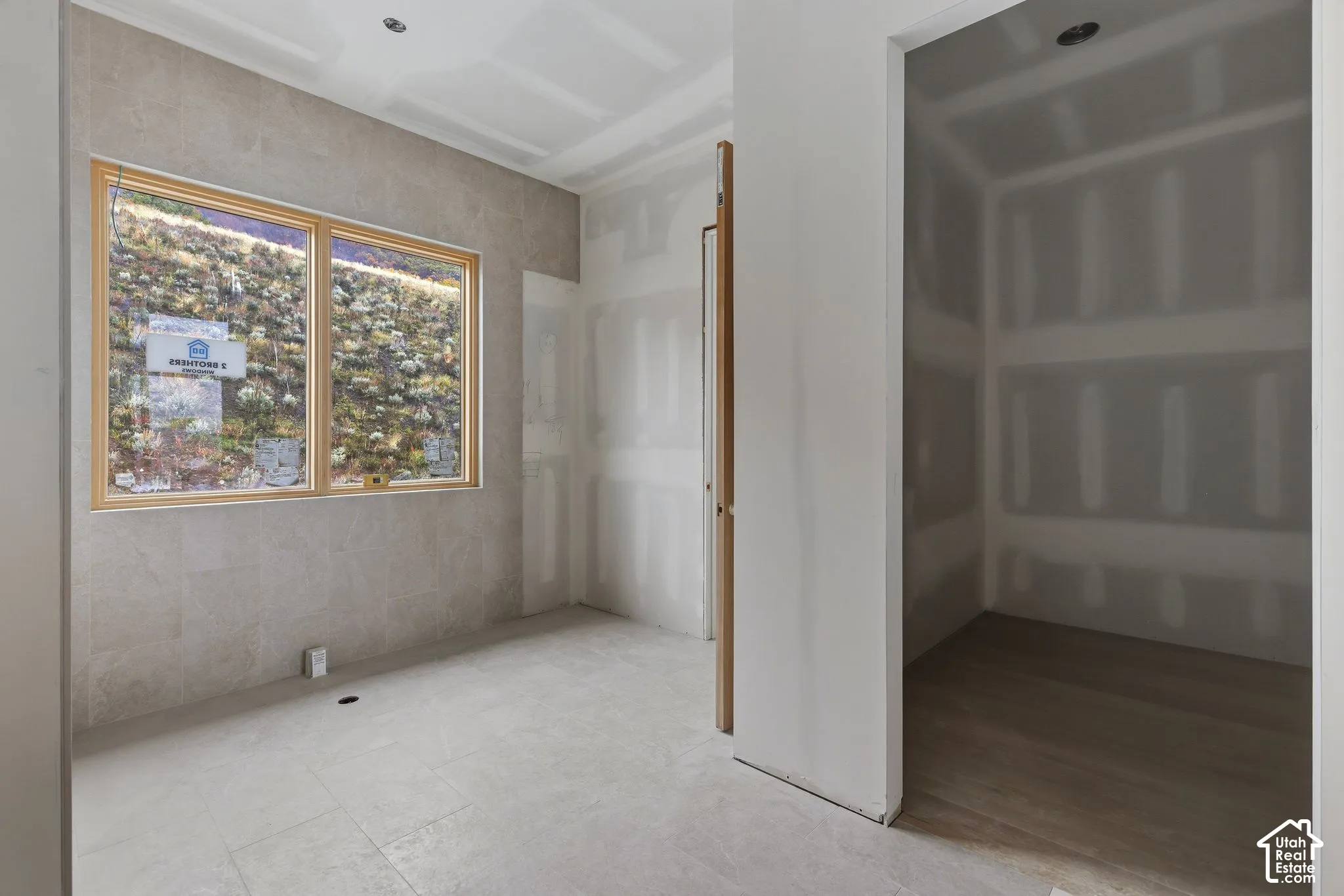 Large picture window with wood-finish trim, neutral stone-finish wall tile, recessed ceiling lighting, and wood-finish flooring