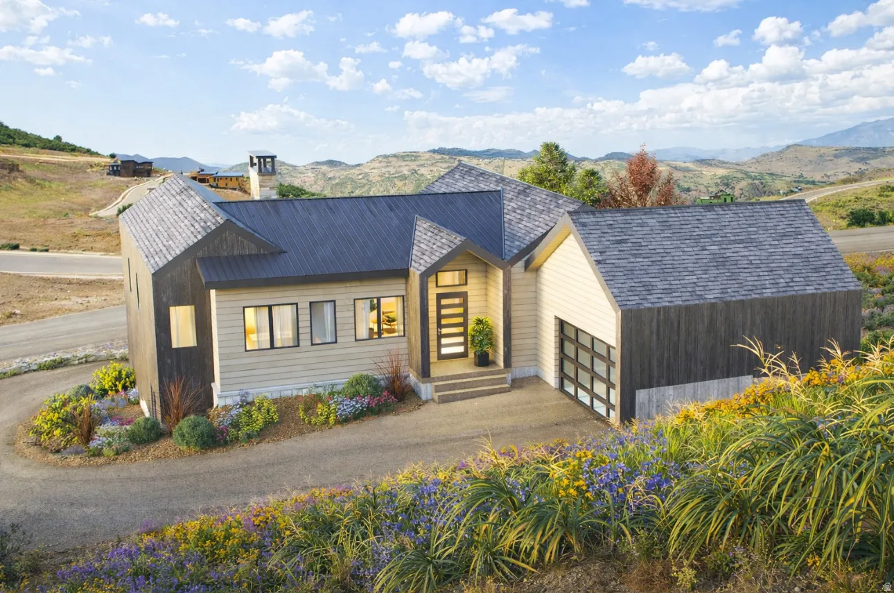 View of front of home with a mountain view, driveway, a chimney, and a garage