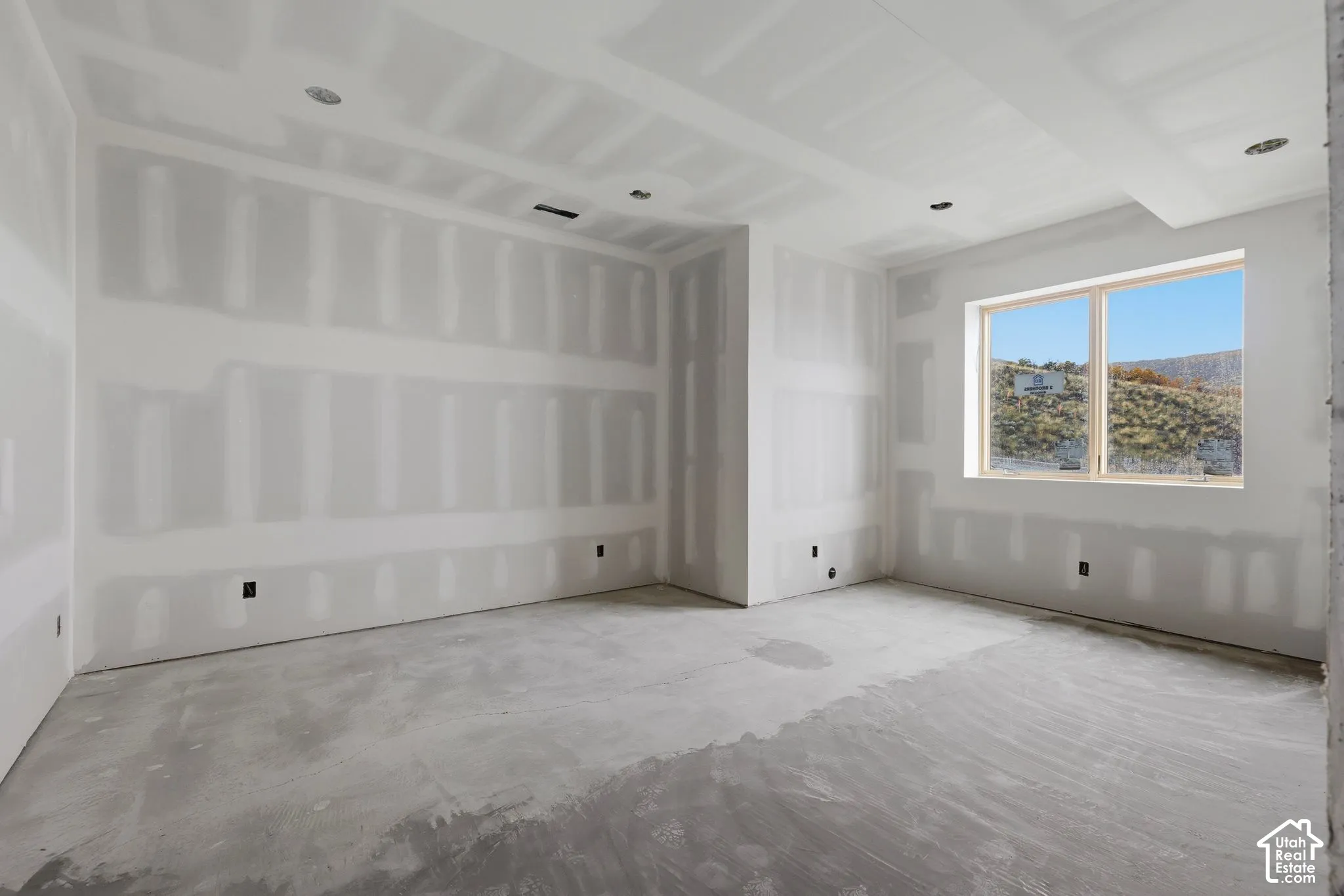 Interior space featuring unfinished drywall, recessed lighting, and a window with mountain scenery