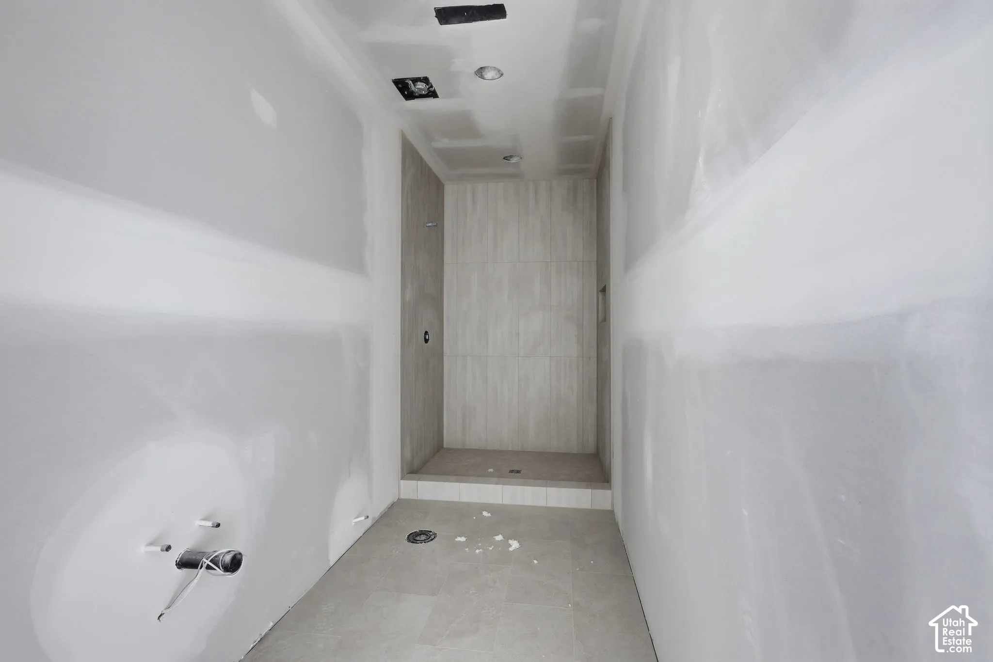 Walk-in shower featuring floor-to-ceiling tile surround, recessed lighting, and a built-in recessed shelf