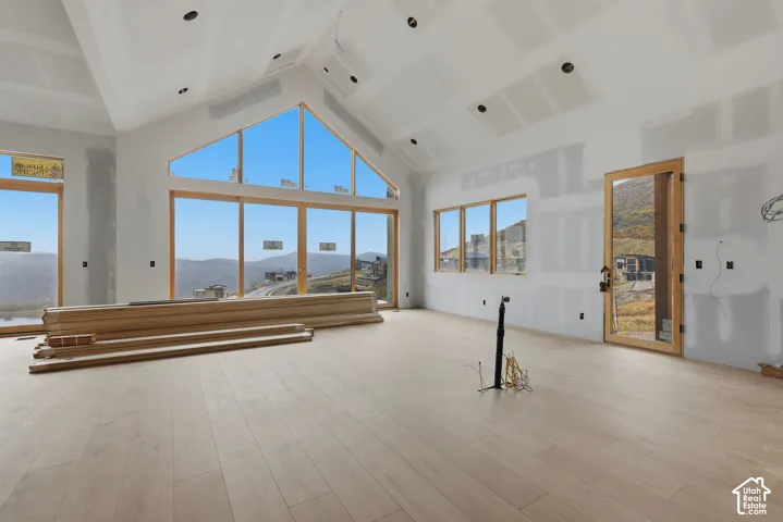 Vaulted ceilings with recessed lighting, wood-finish flooring, floor-to-ceiling windows, and mountain scenery