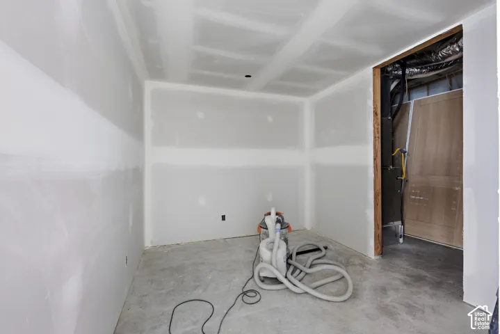 Unfinished room featuring drywall installation, concrete flooring, and exposed mechanical components