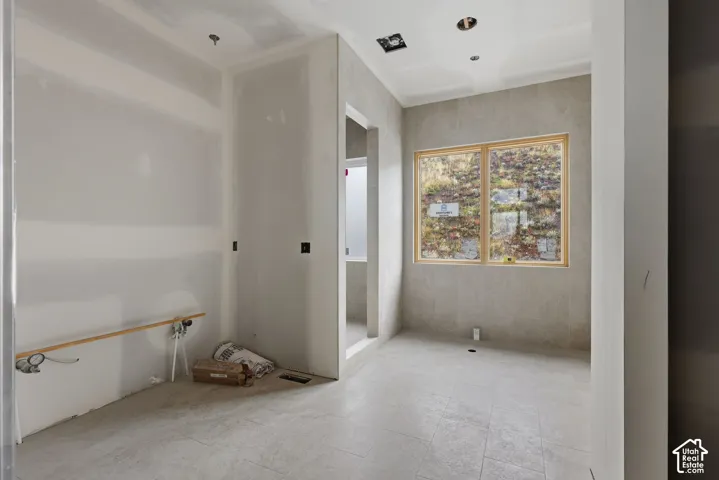 Interior space featuring large-format neutral tile flooring and wall-to-ceiling tilework, a wood-frame window, and recessed ceiling lighting
