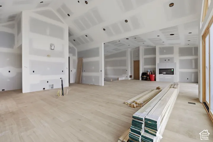 Open-concept interior featuring vaulted ceilings, wood-finish flooring, recessed lighting, and a built-in linear fireplace