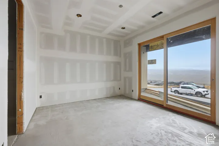 Interior space featuring unfinished drywall surfaces, wood-frame sliding glass doors, recessed lighting, and exposed landscape scenery
