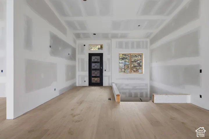 Light-toned wood-finish flooring, entry door with decorative glass inlay, transom window, and dual-pane window