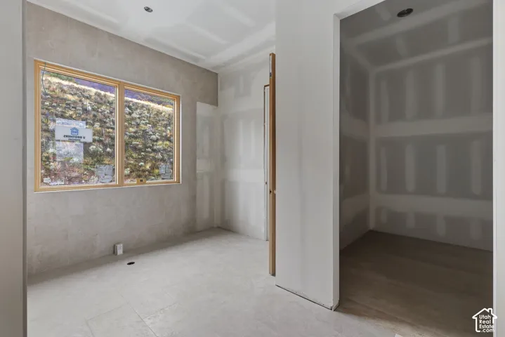 Large picture window with wood-finish trim, neutral stone-finish wall tile, recessed ceiling lighting, and wood-finish flooring