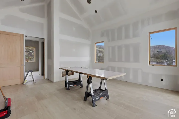 Vaulted ceiling, wood-finish flooring, and natural light via multiple windows with exterior mountain scenery