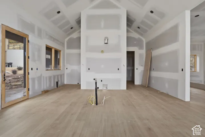Vaulted ceilings, wood-finish flooring, recessed lighting, and wooden window frames
