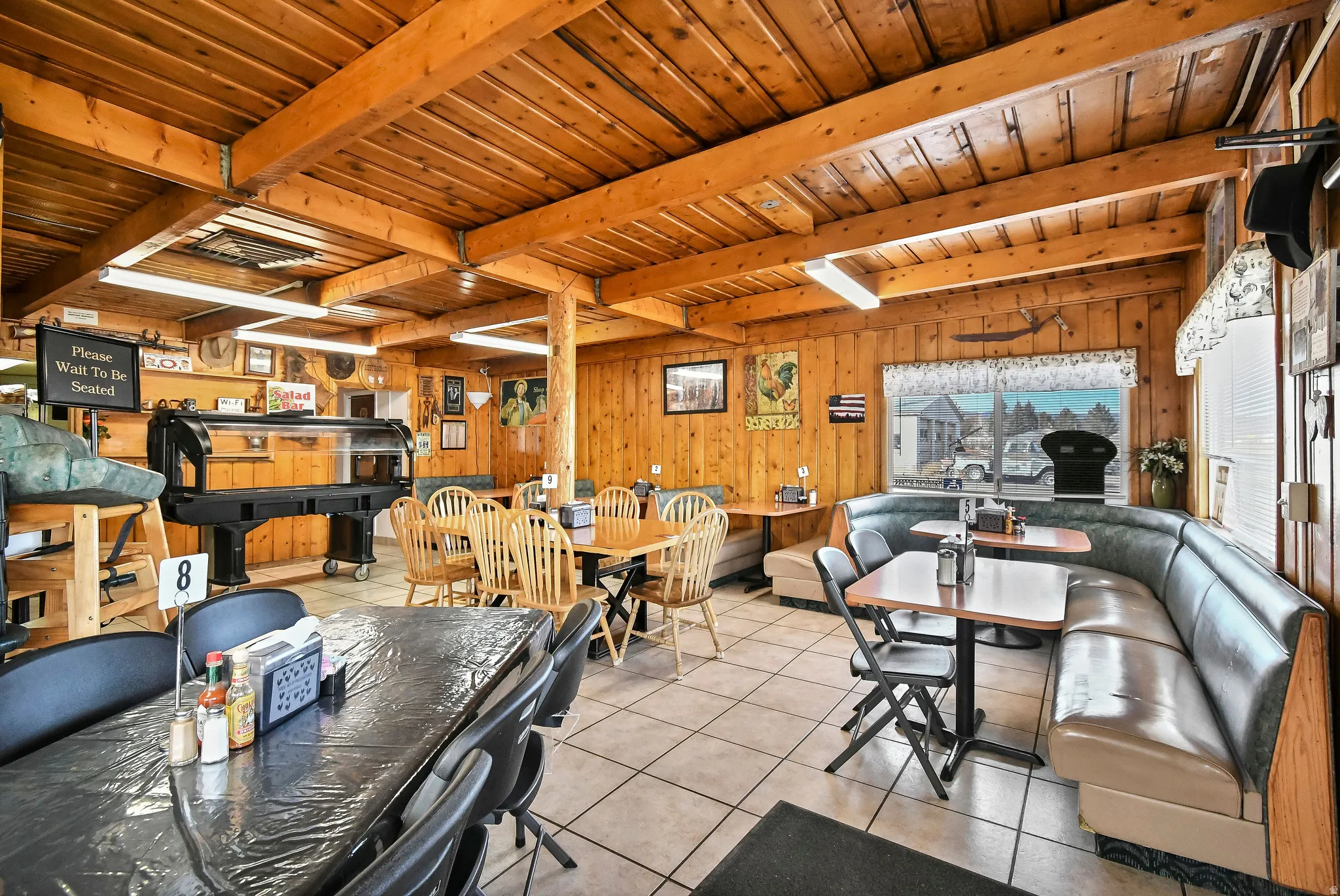 Dining room featuring a wooden ceiling with exposed beams, light tile patterned floors, and wood walls
