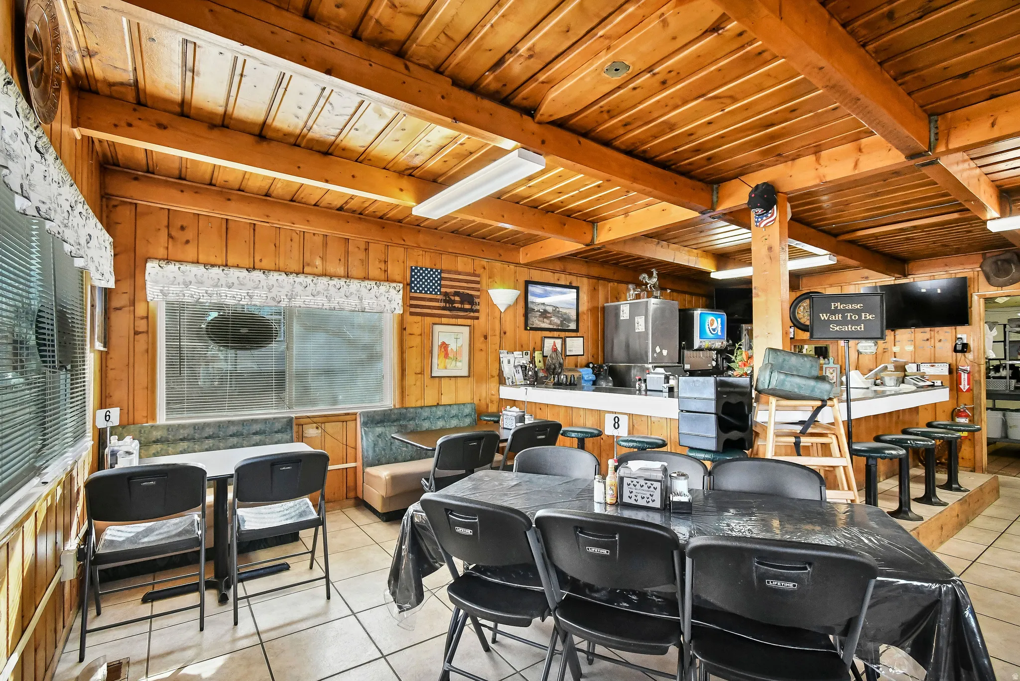 Dining room with light tile patterned floors, a wood ceiling with exposed beams, and wood walls