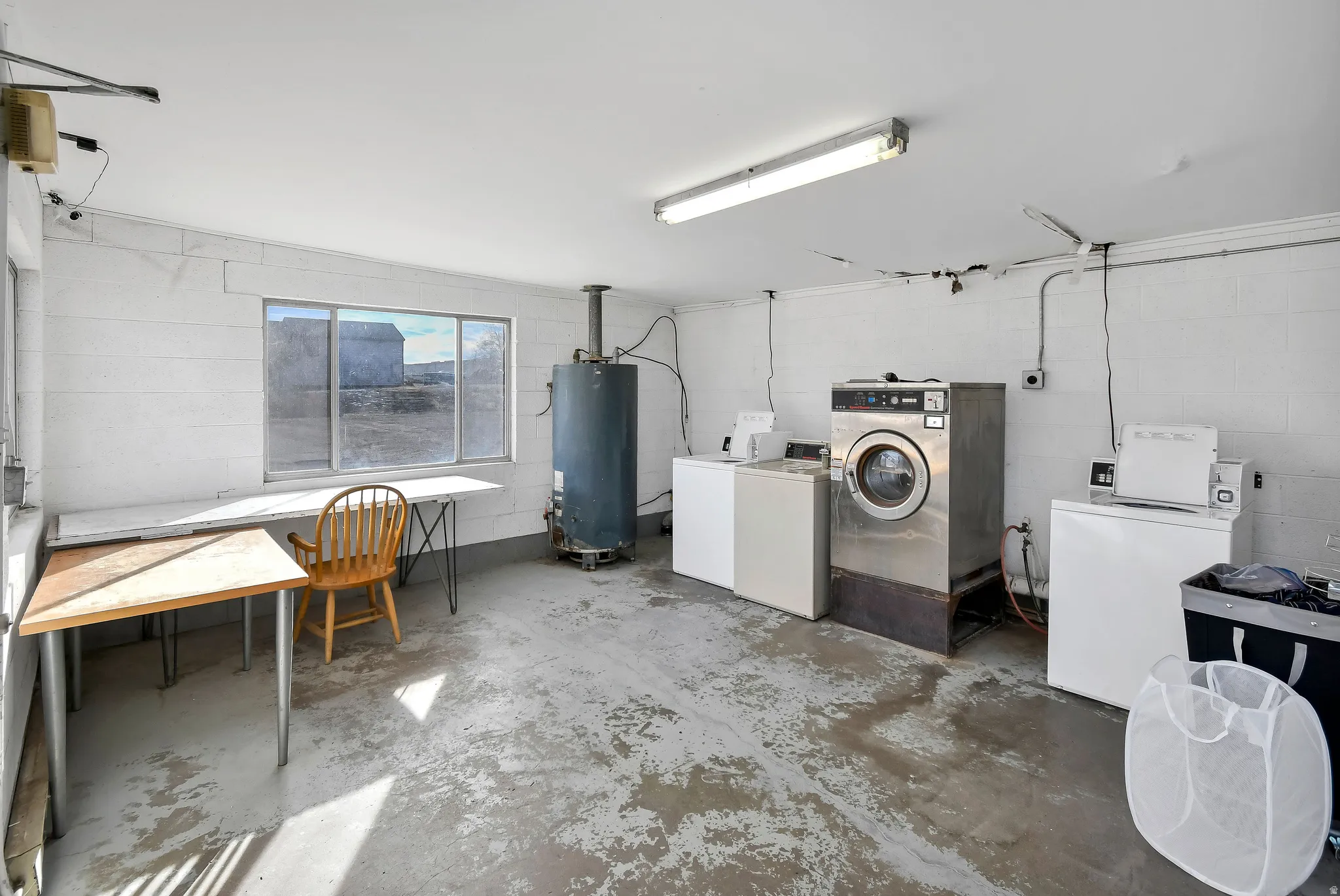 Community laundry featuring concrete block wall, washing machine and dryer, and concrete floors