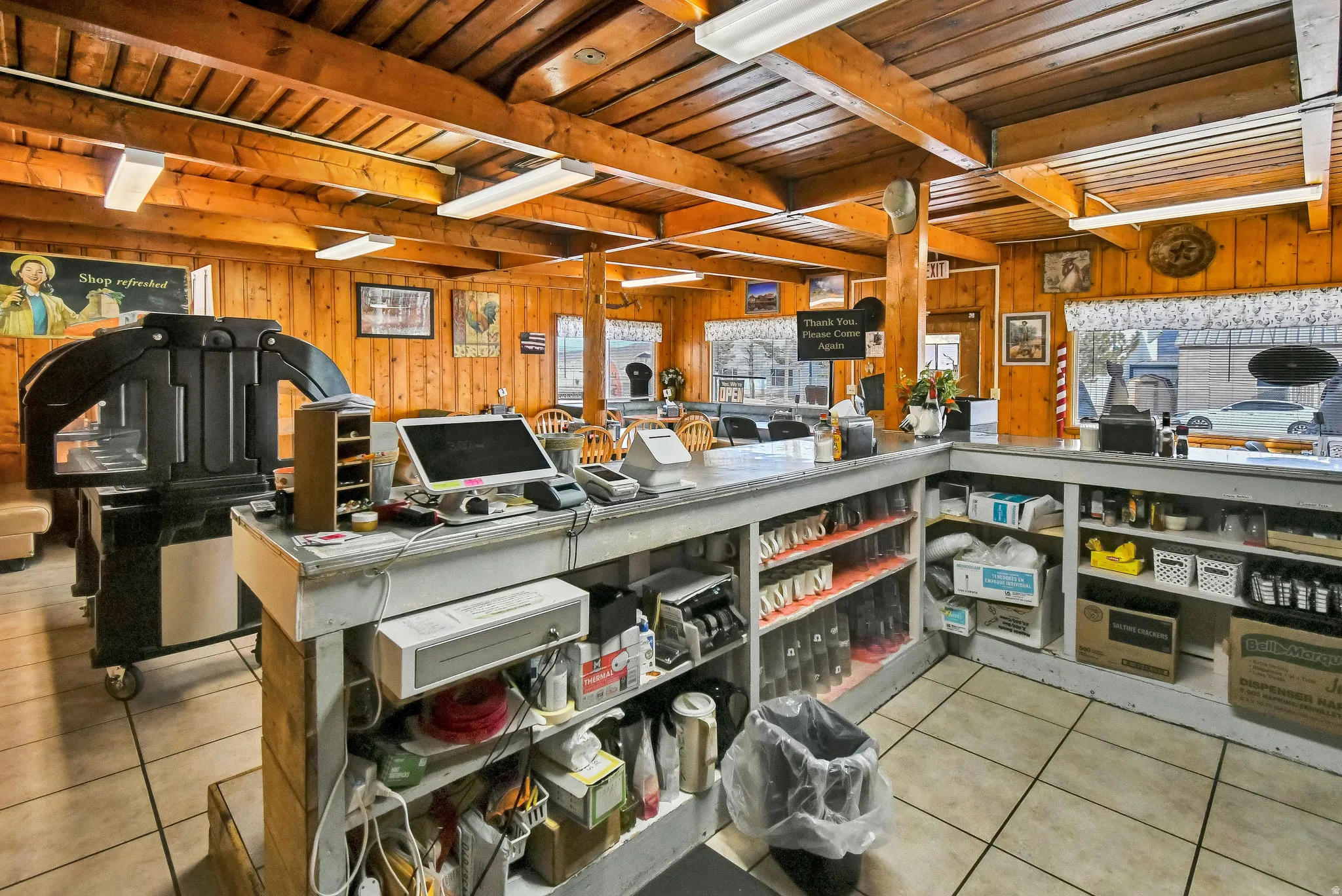 Kitchen featuring light tile patterned floors, a wooden ceiling with exposed beams, and wood walls