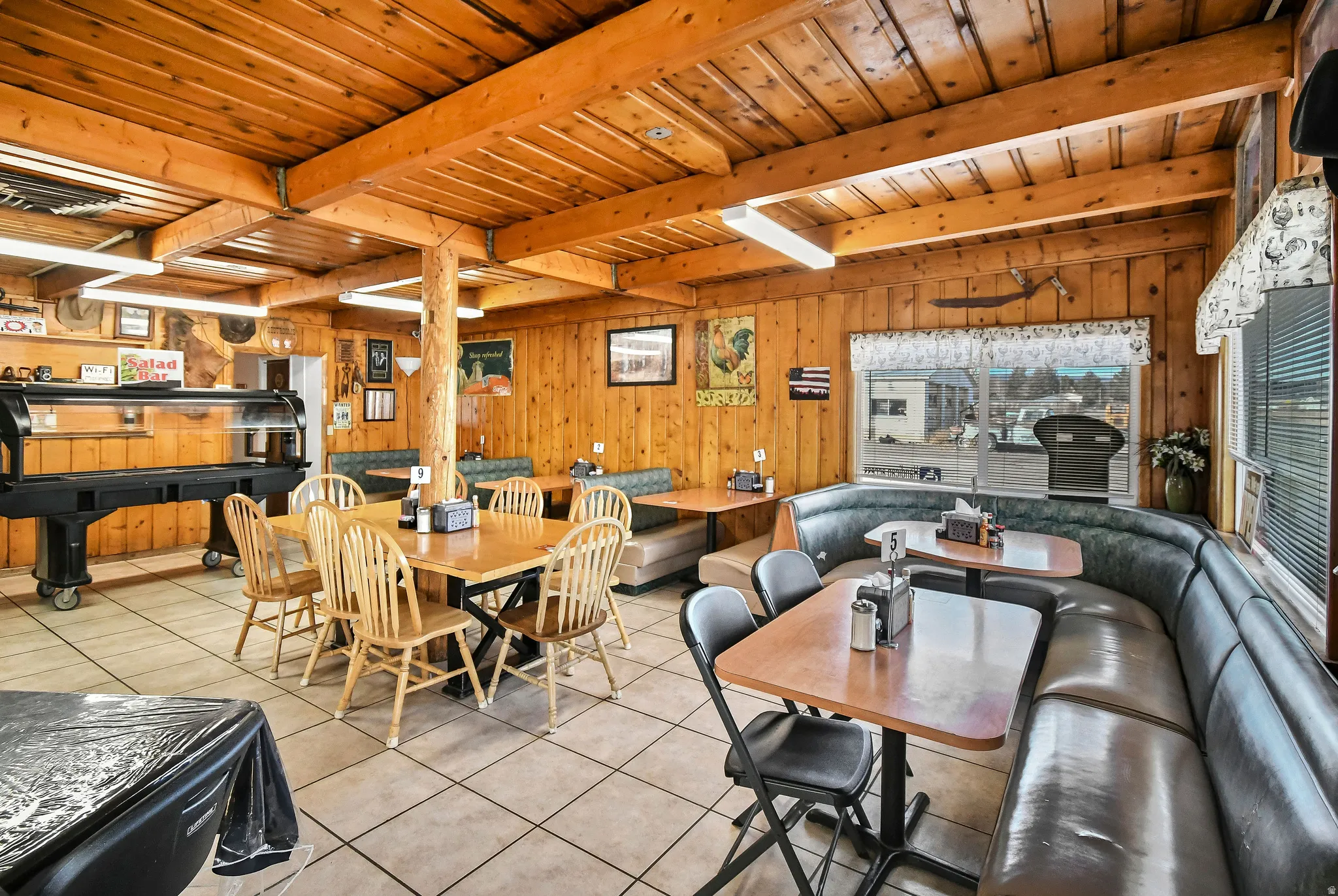 Tiled dining area with a wooden ceiling with exposed beams and wooden walls