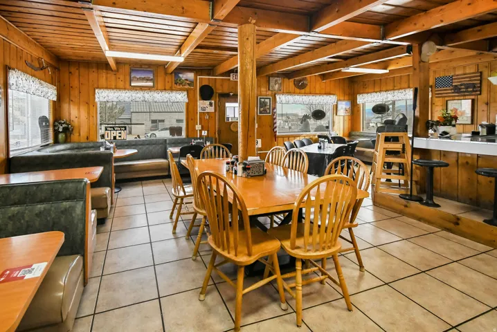 Dining space with light tile patterned flooring, a wood ceiling with exposed beams, and wood walls